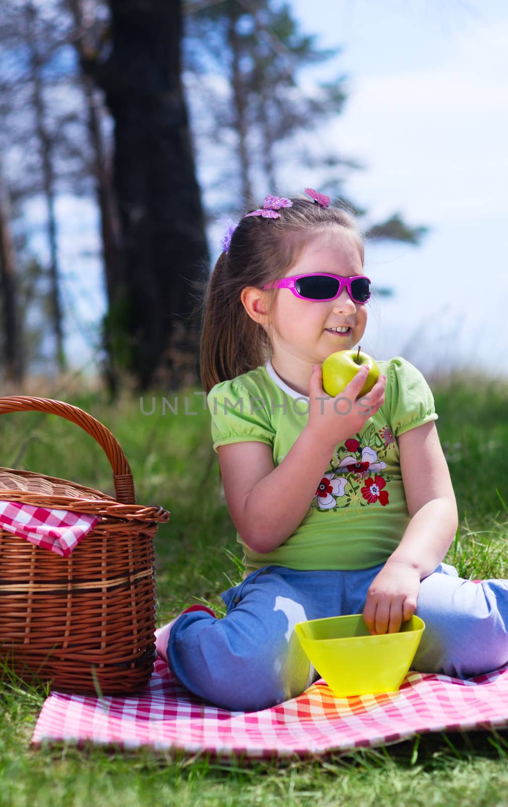 Little girl with apple and picnic basket at forest