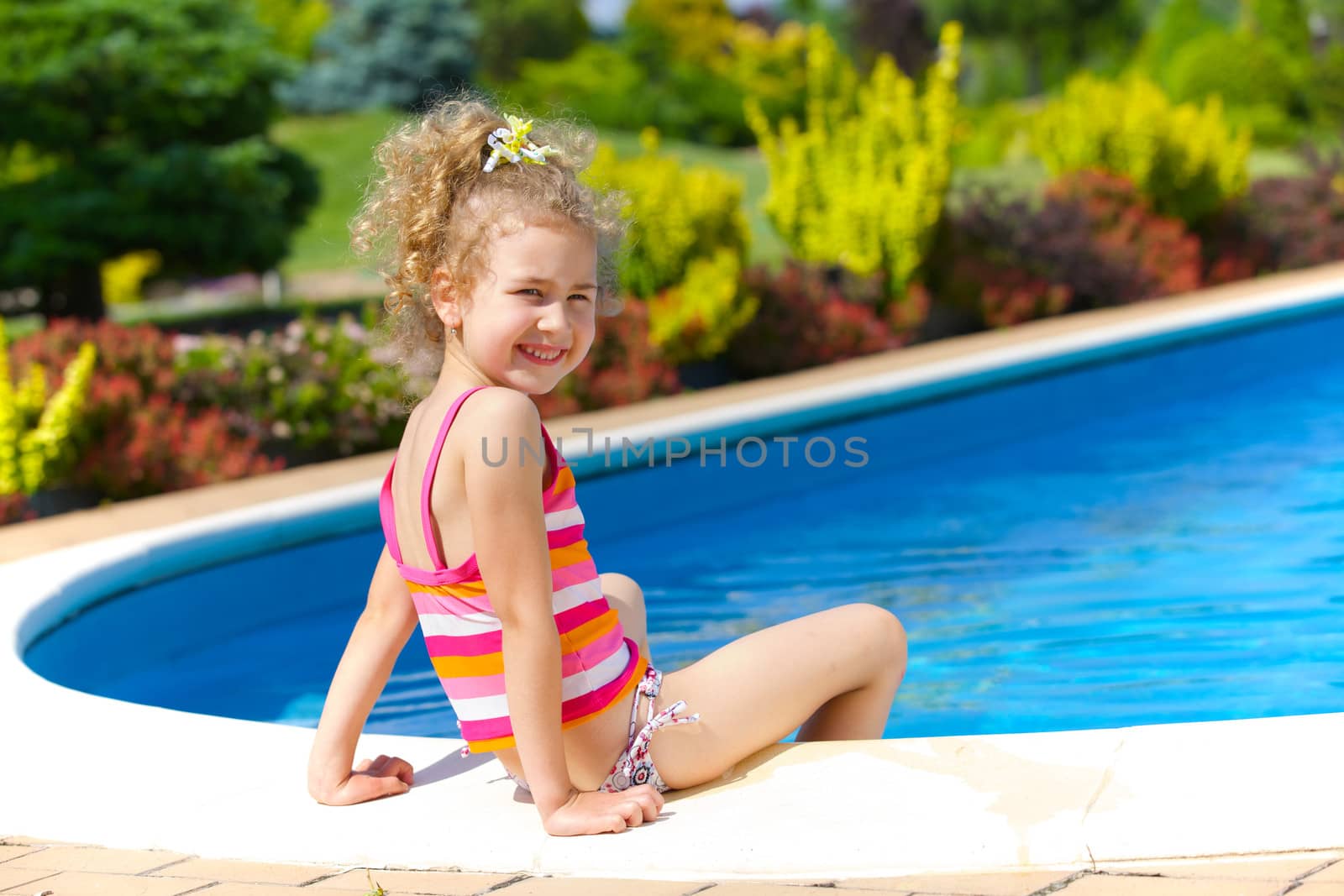 Pretty little girl sitting near swimming pool