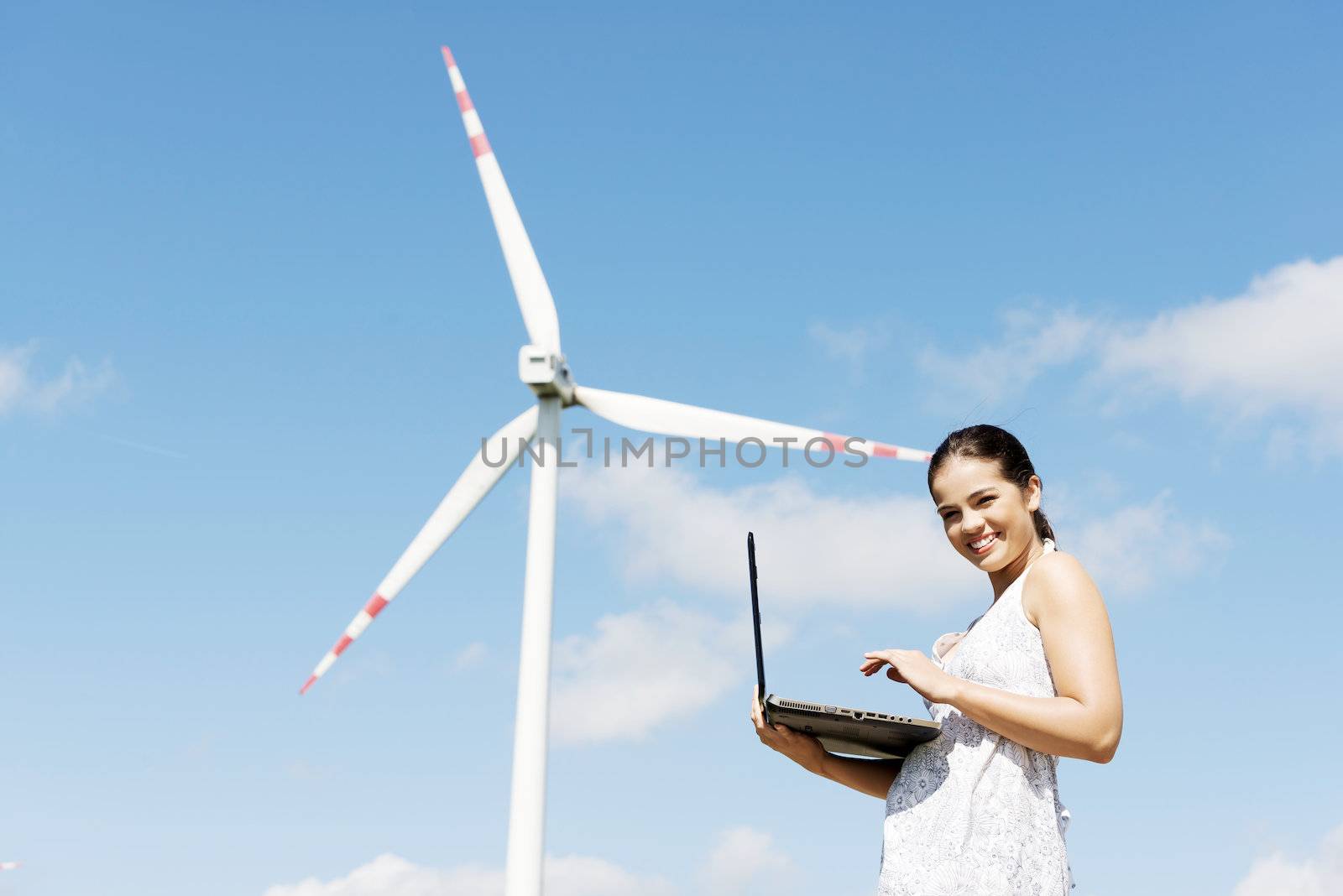 Teen girl with laptop next to wind turbine. by BDS