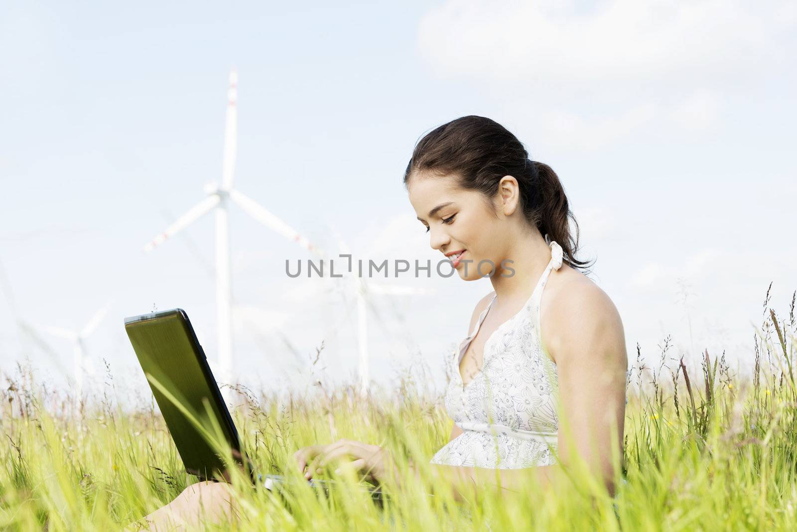 Teen girl with laptop next to wind turbine. by BDS