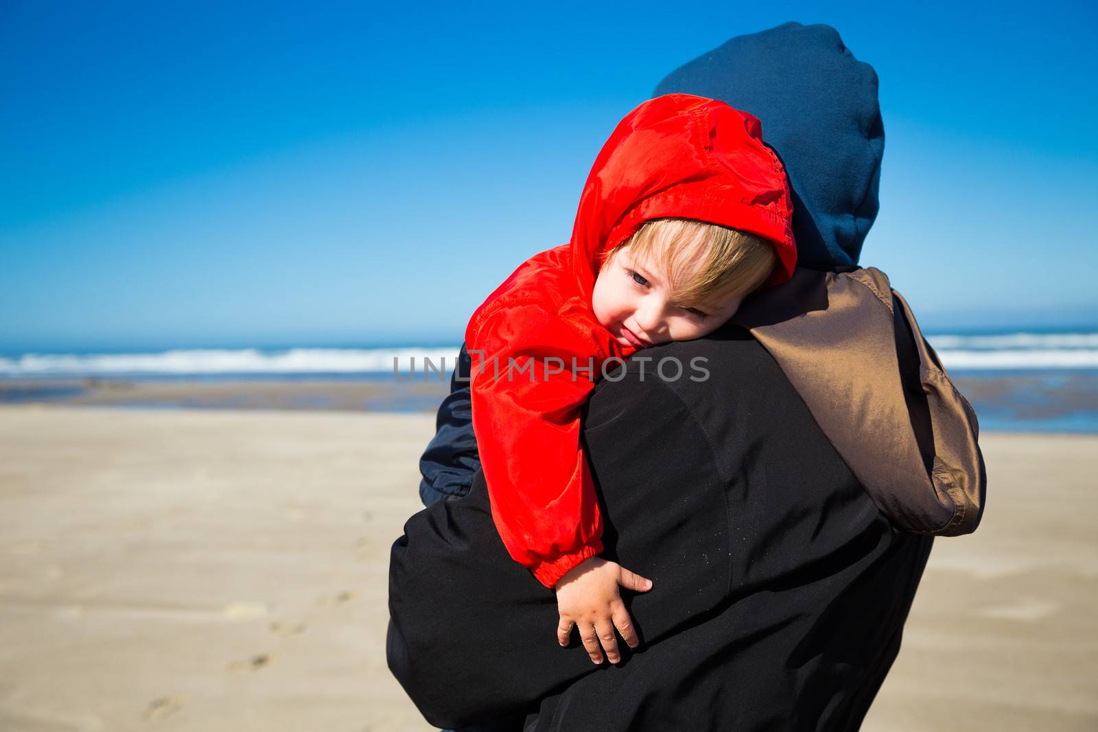 A very sleep kid rests in the arms of his grandmother after playing at the beach in the Pacific northwest.