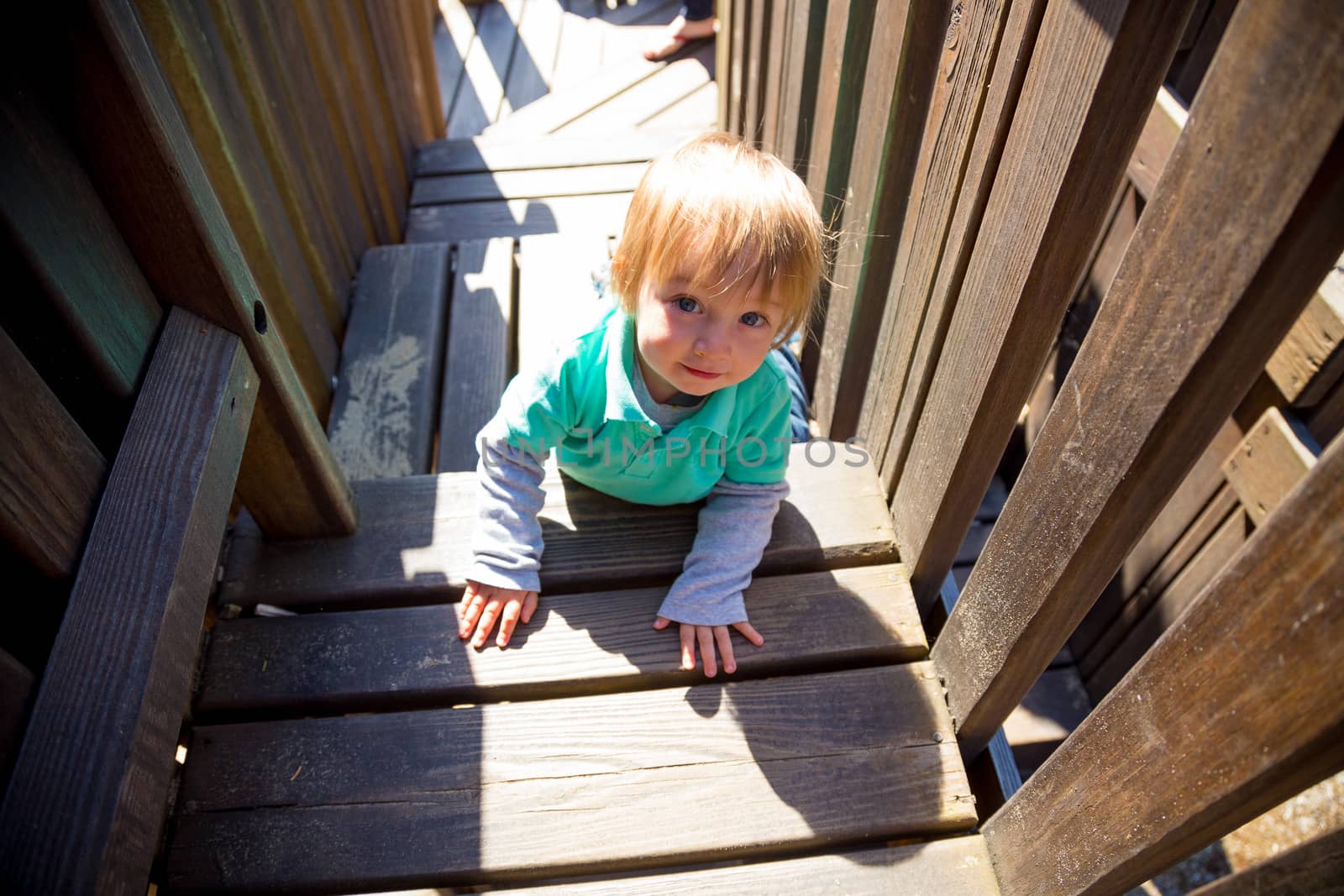 A cute young boy climbs the wooden stairs at a playground in a park in Lincoln City Oregon.