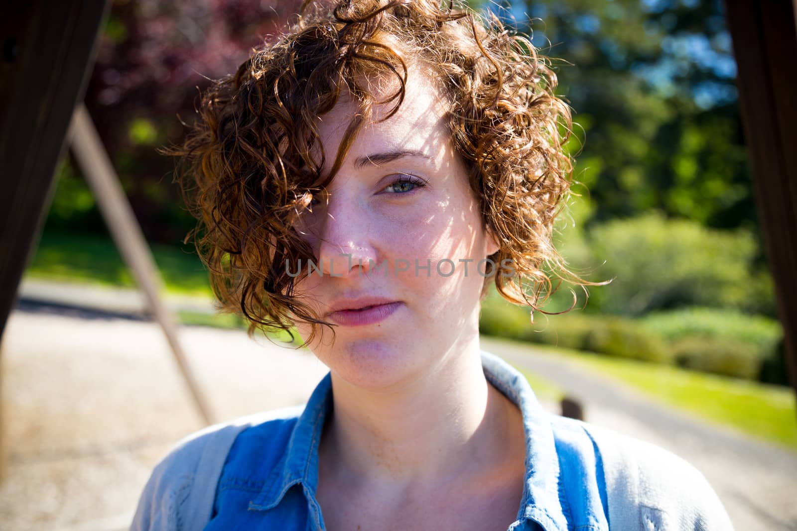 This attractive woman poses for a portrait outdoors with a simple out of focus background in color and horizontal.