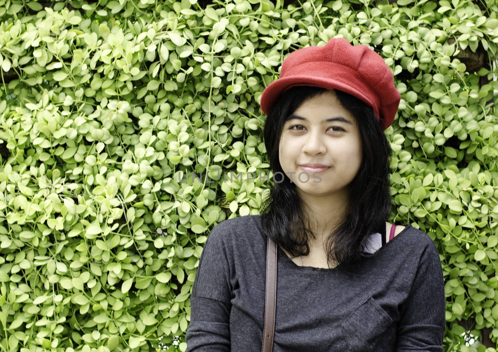 Asian girl with red hat in park on a background of green nature 