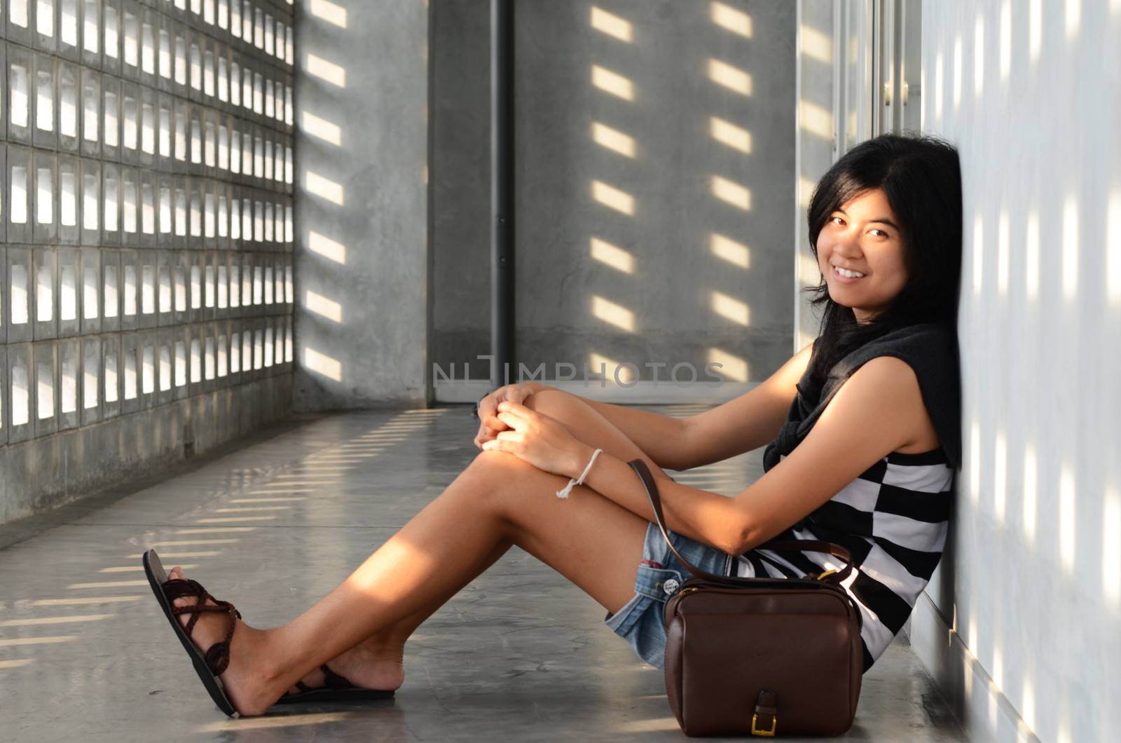 Asian woman sitting on corridor floor by siraanamwong