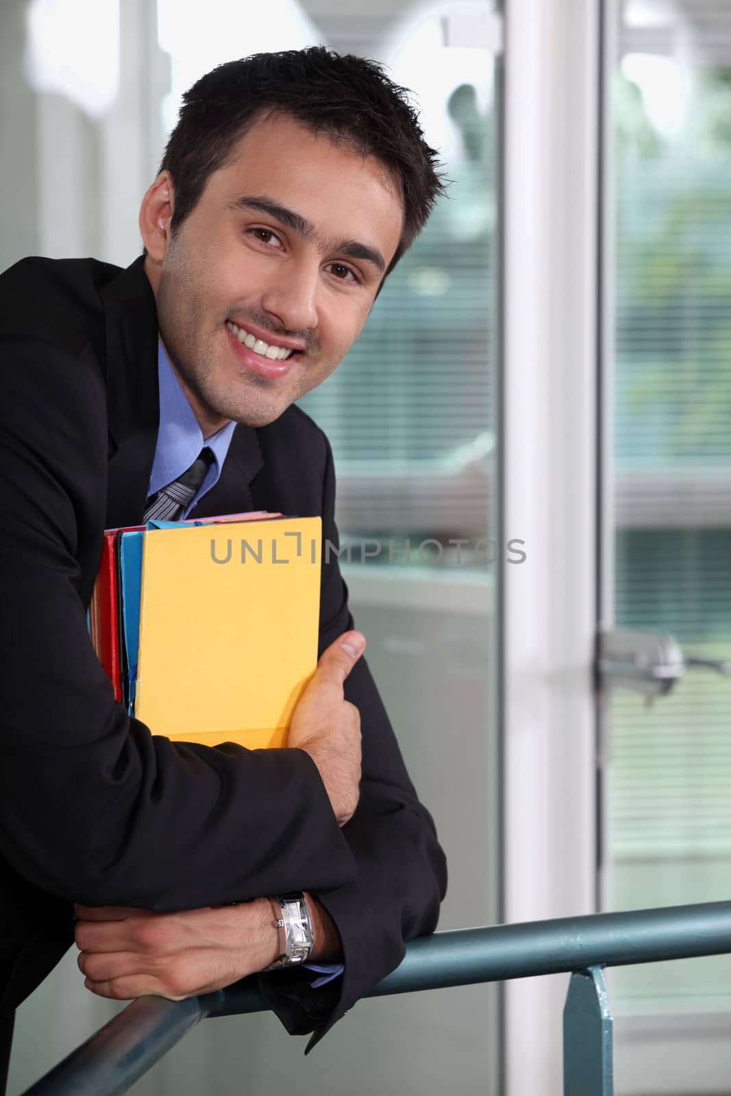Smiling businessman holding files by phovoir
