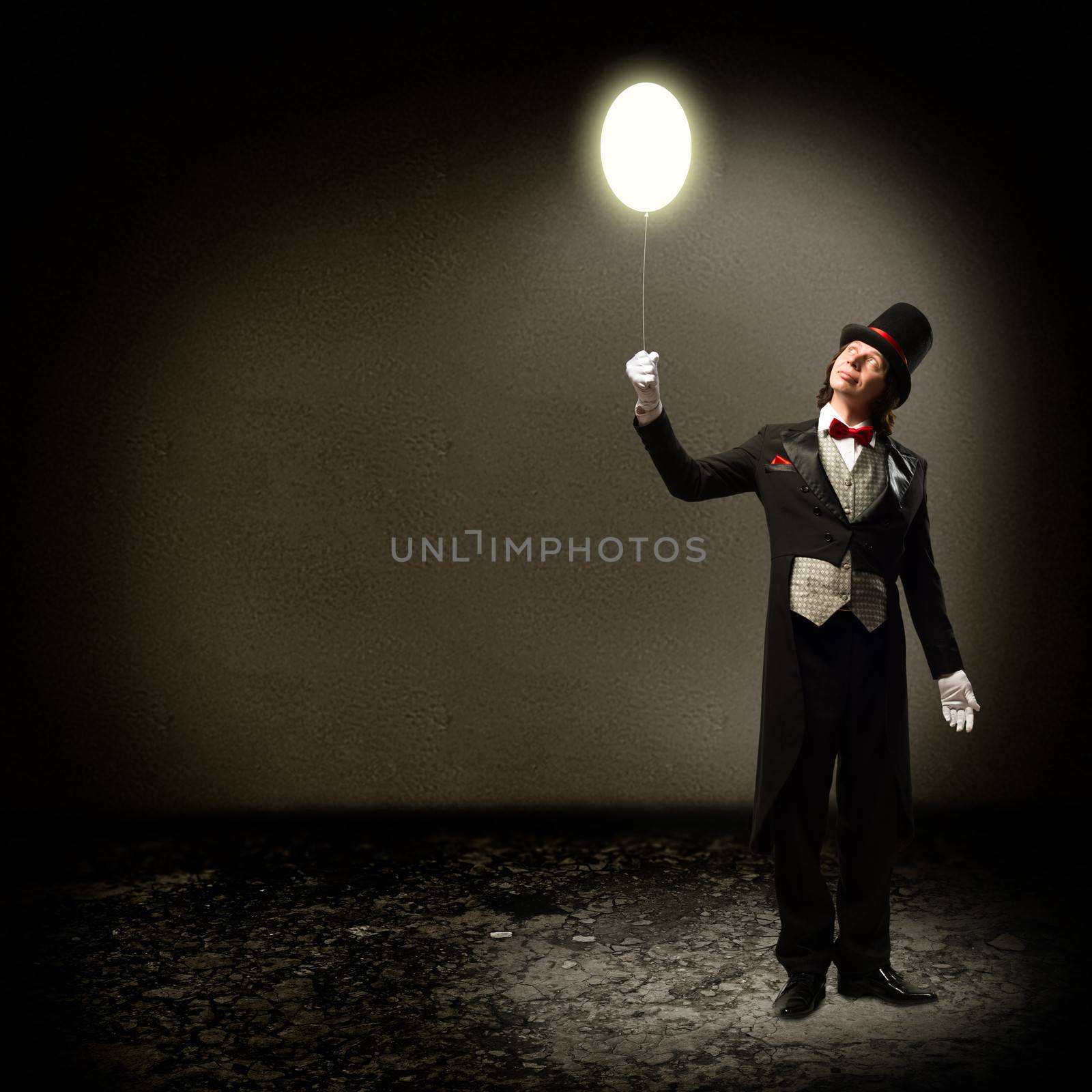 magician in top hat and tie, holding a glowing baloon, and staring at him