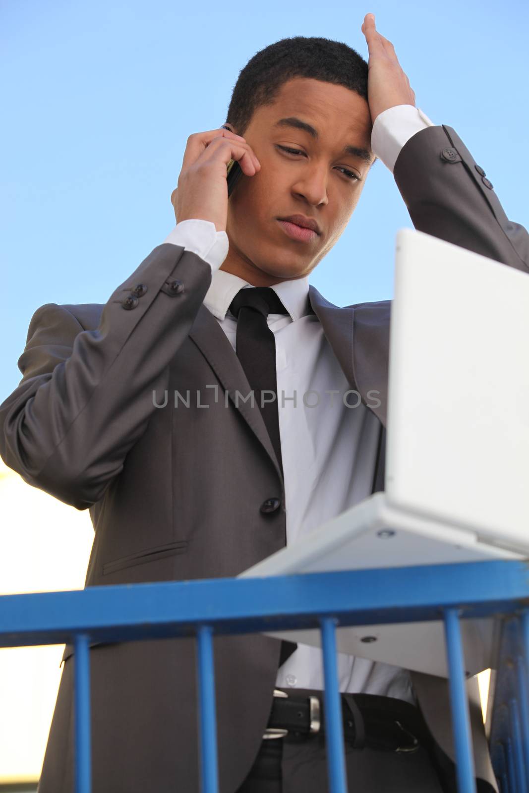 Stressed young businessman with laptop by phovoir