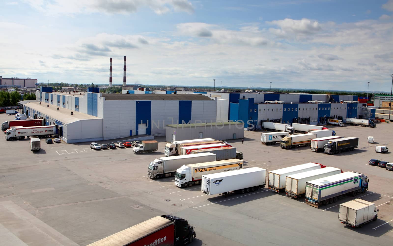 Cargo terminal in a large warehouse complex. Trucks unload, unloading or waiting in the parking lot in front of the warehouse. by grigvovan