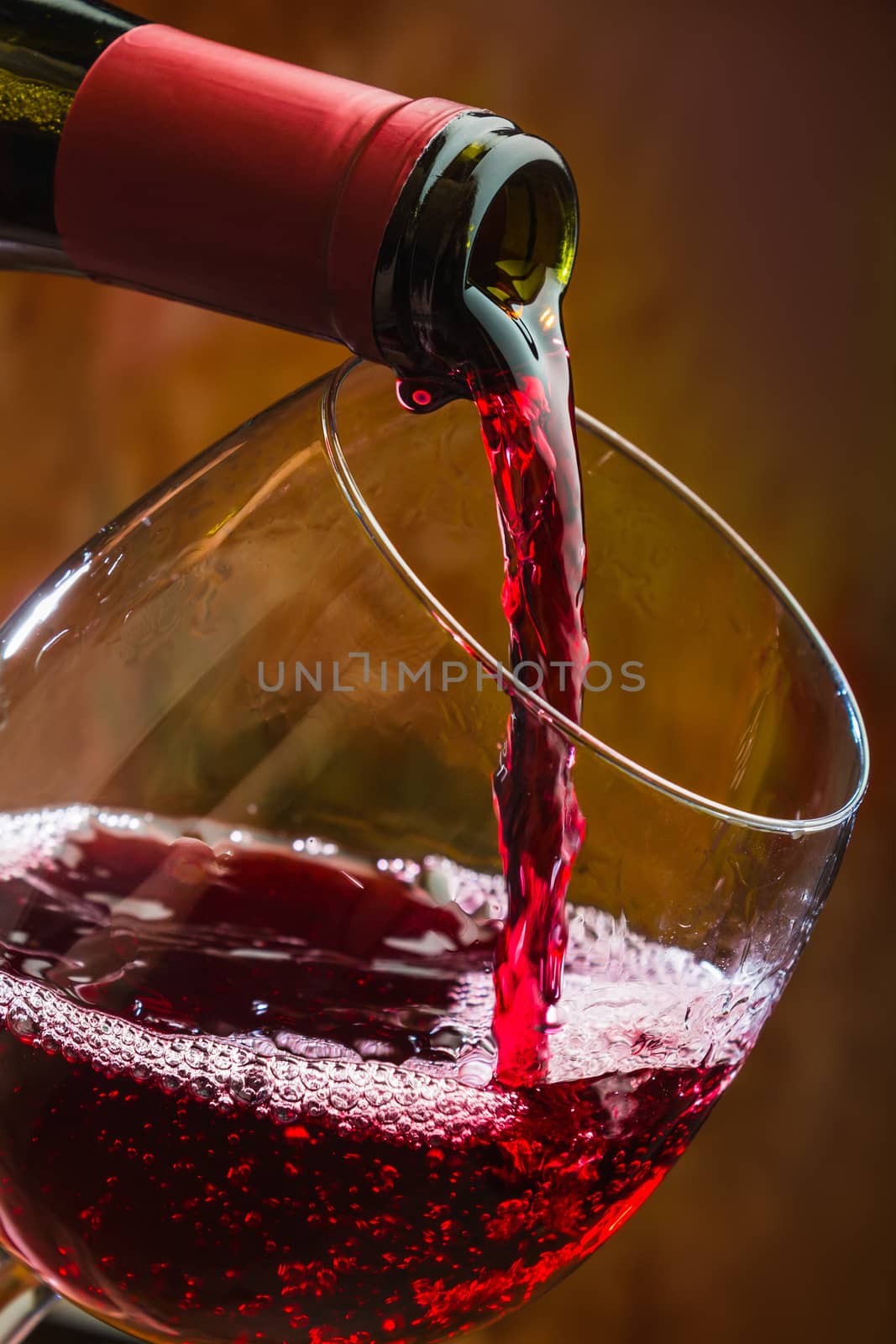 Wine pours into the glass of the bottle on a colored background