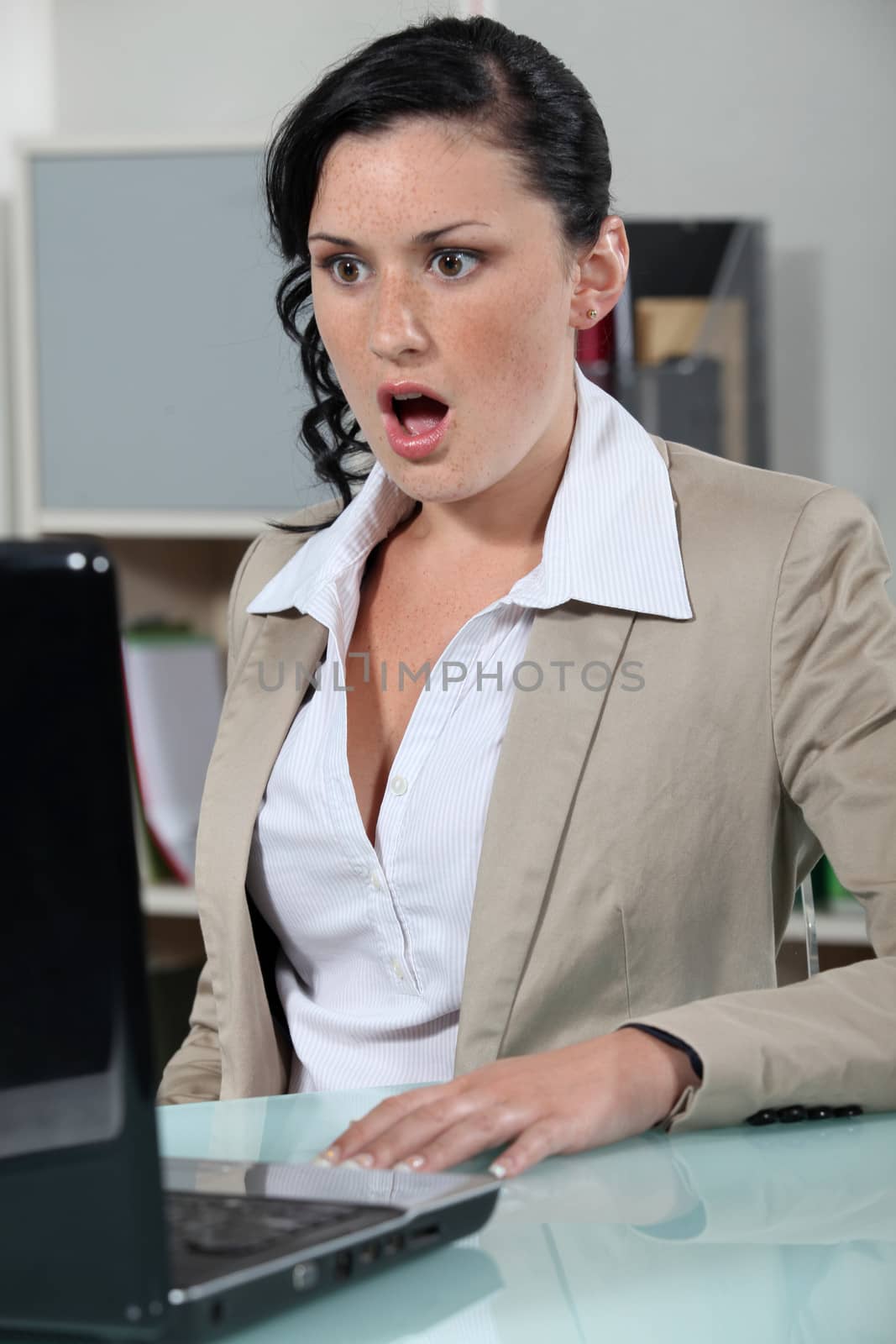 businesswoman looking at her laptop open mouthed by phovoir