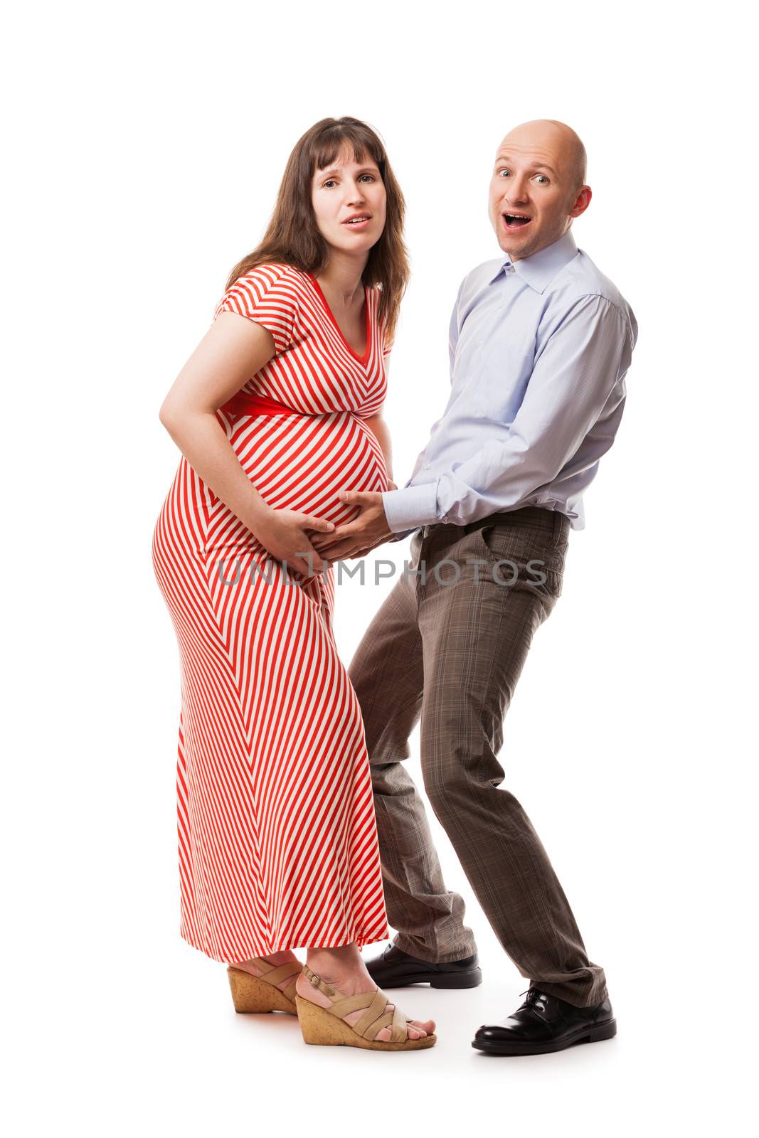 Pregnancy and new life concept - amazed or surprised parents holding pregnant woman abdomen