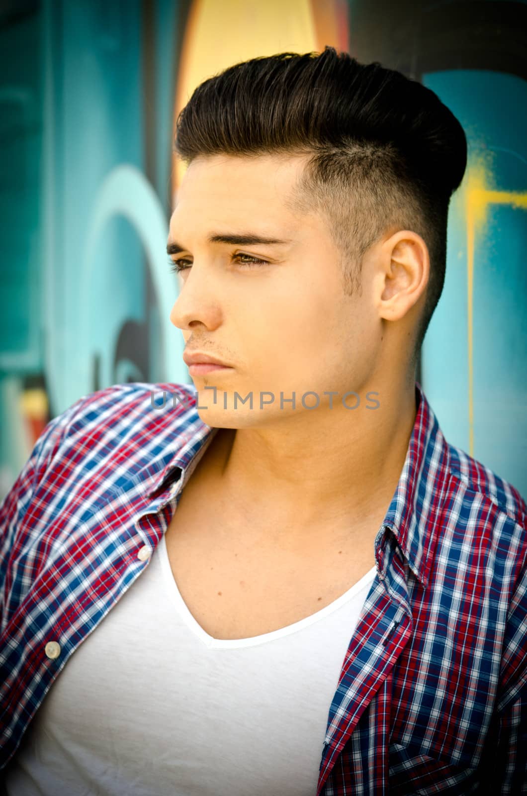Profile of handsome young man against colorful graffiti covered wall