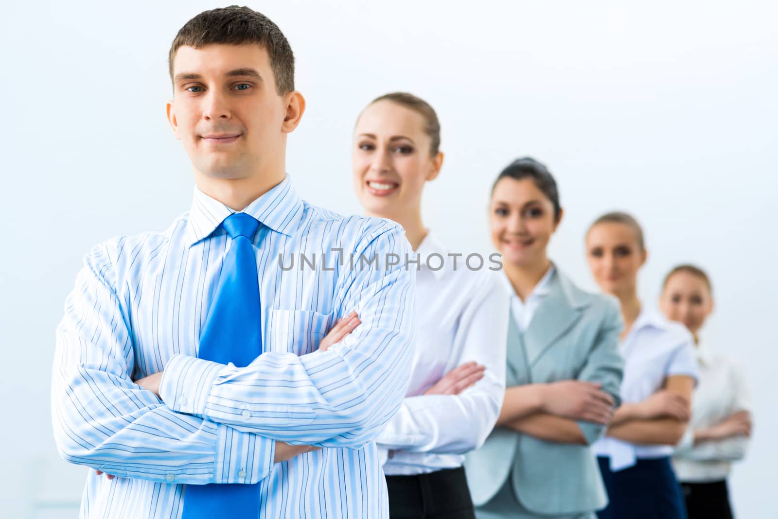 group of business people standing in a row, smiling and crossing his arms