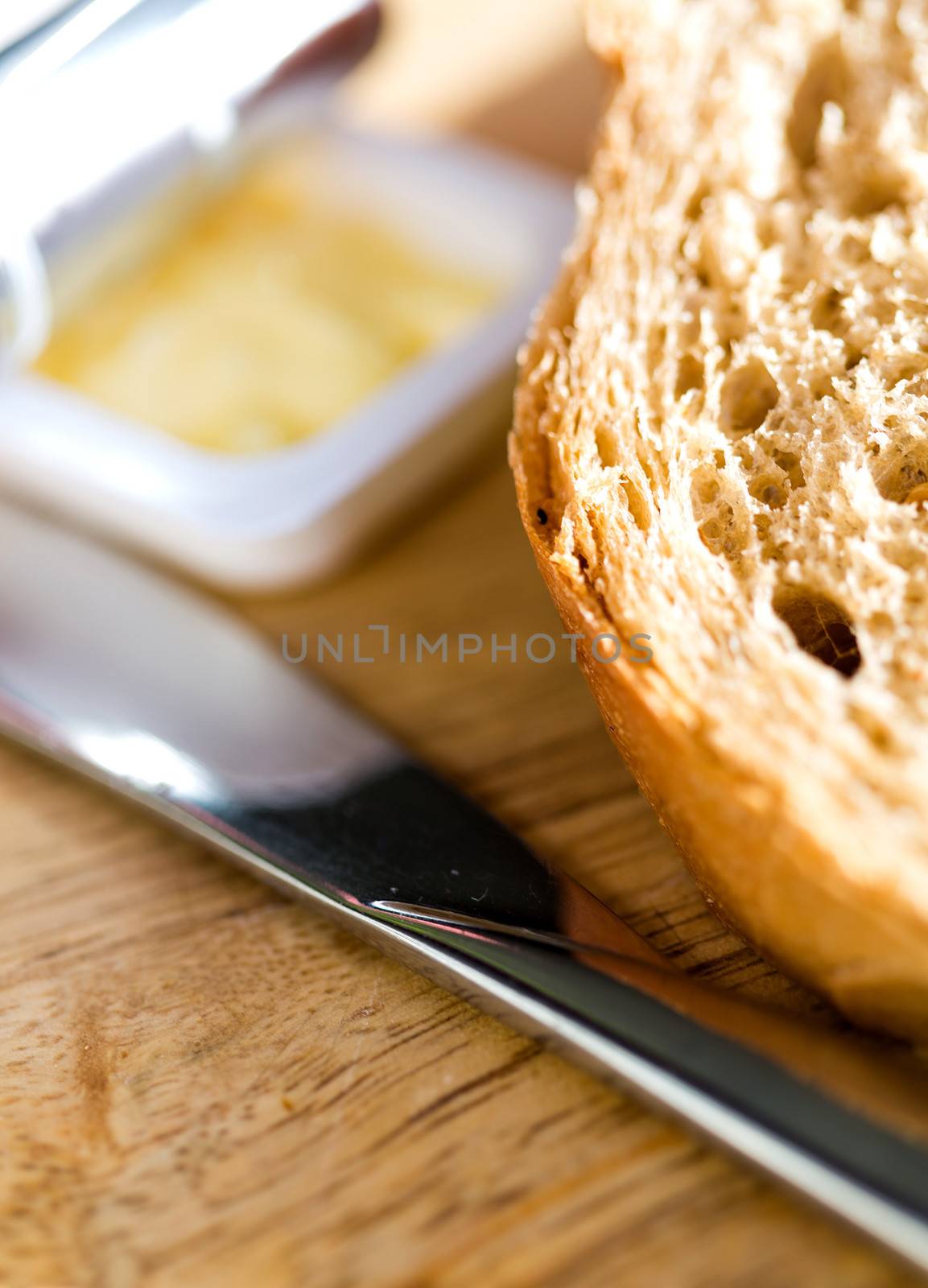 Cropped image of bread and fresh butter with knife on table