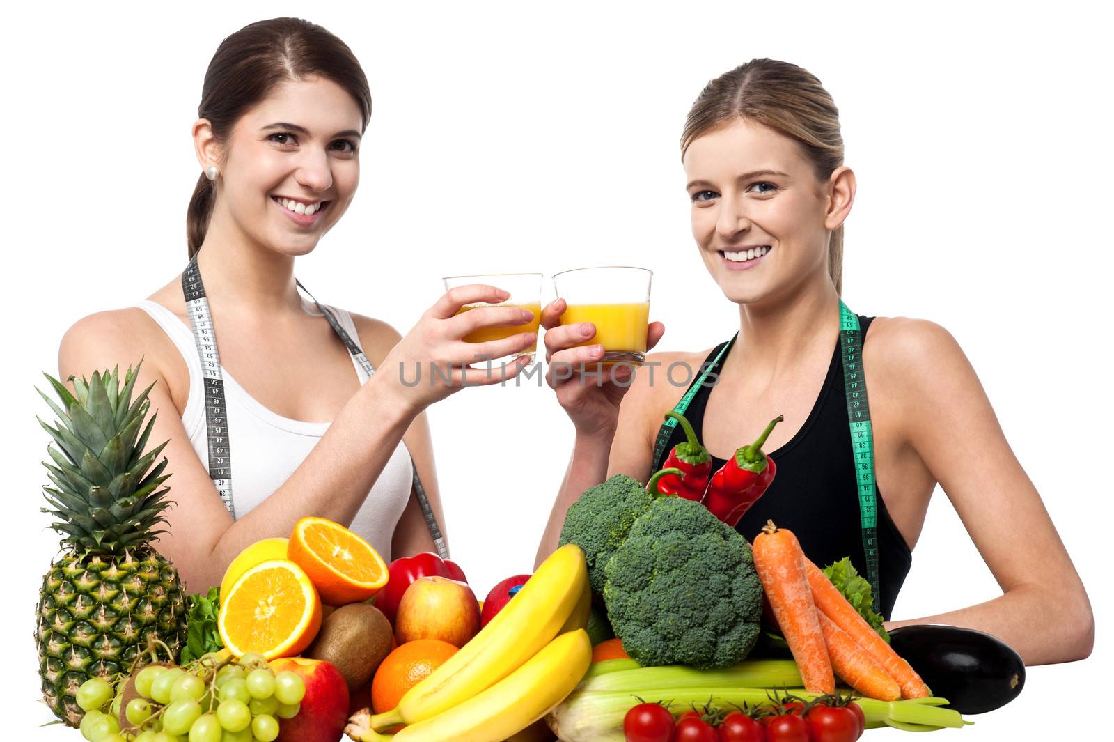 Young smiling girls each holding glass of juice by stockyimages