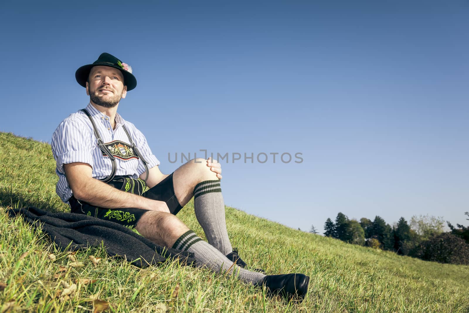 An image of a traditional bavarian man relaxing in the grass