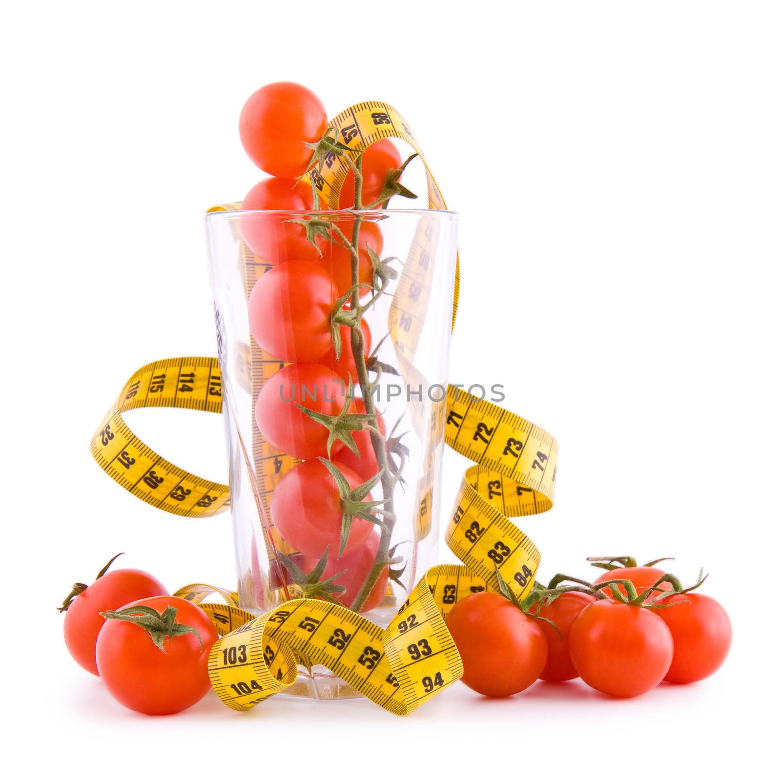 Small tomatoes in a glass and tailor tape isolated on white