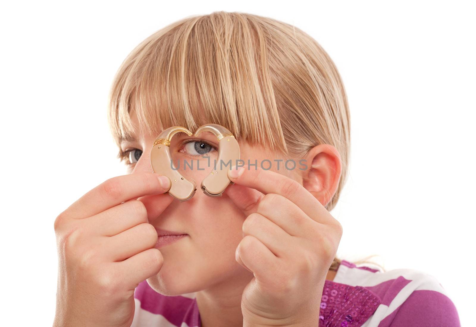 Young female looking through a heart shape forming from two hearing aids