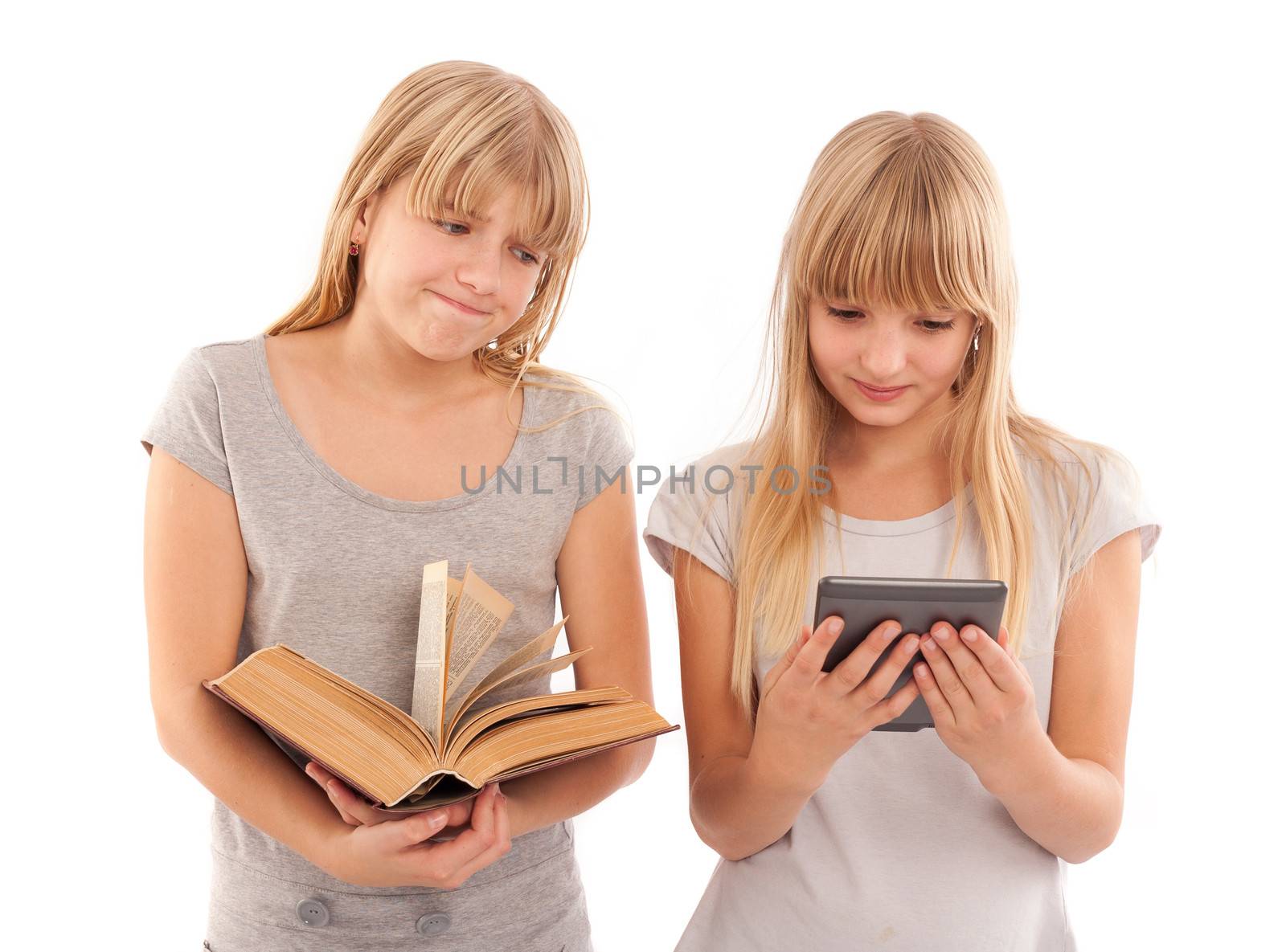 Ebook vs book - Girl holding a big book and her girlfriend reading an ebook reader tablet device.