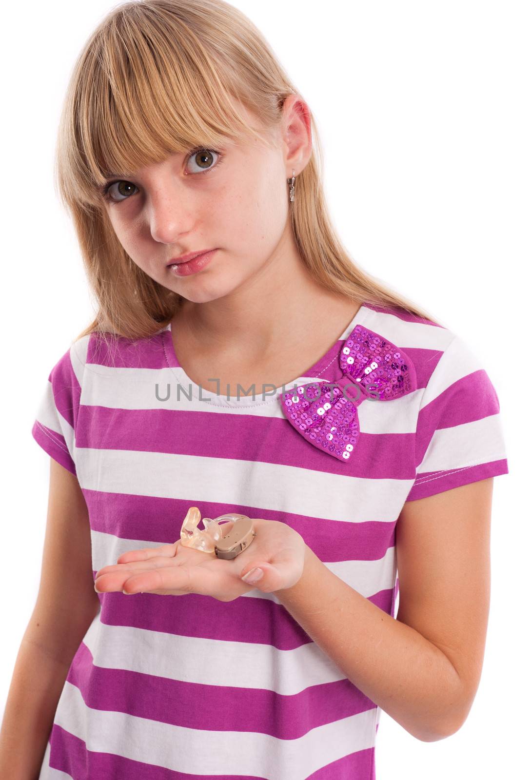 Girl showing her hearing aid in front of a white background.