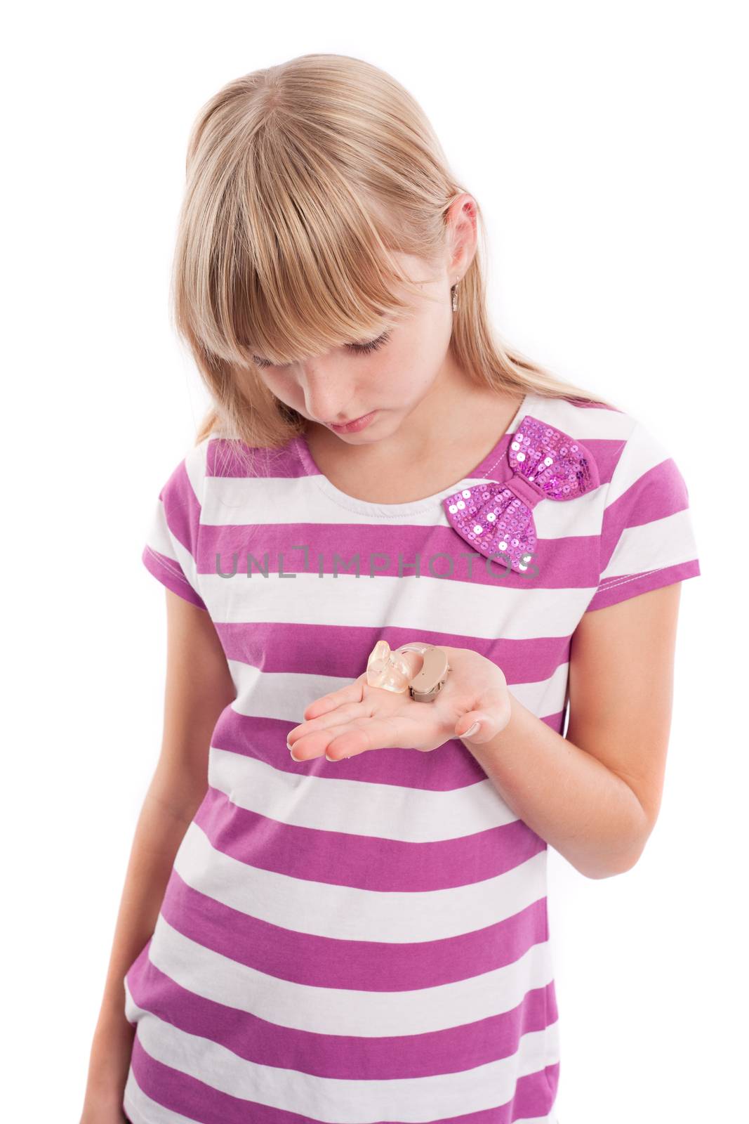 Young girl holding a digital behind-the-ear hearing aid with earmould and tubing on her palm. Isolated on white.