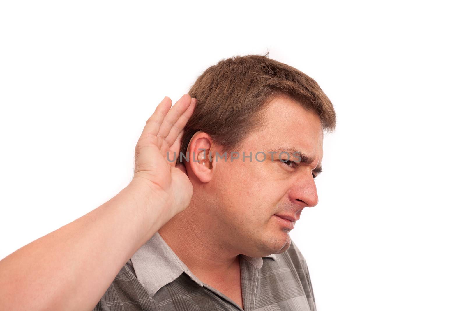 I can't hear you - Middle aged deaf man wearing hearing aids cupping hand behind ear on white background