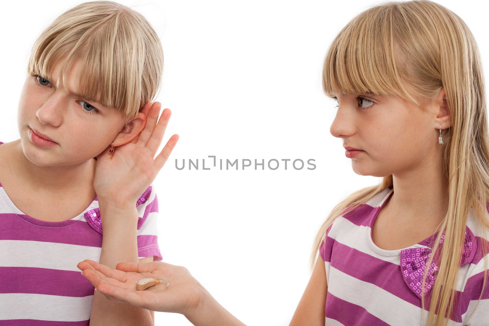 Girl offering a hearing aid to another girl who can't hear well. Isolated on white.
