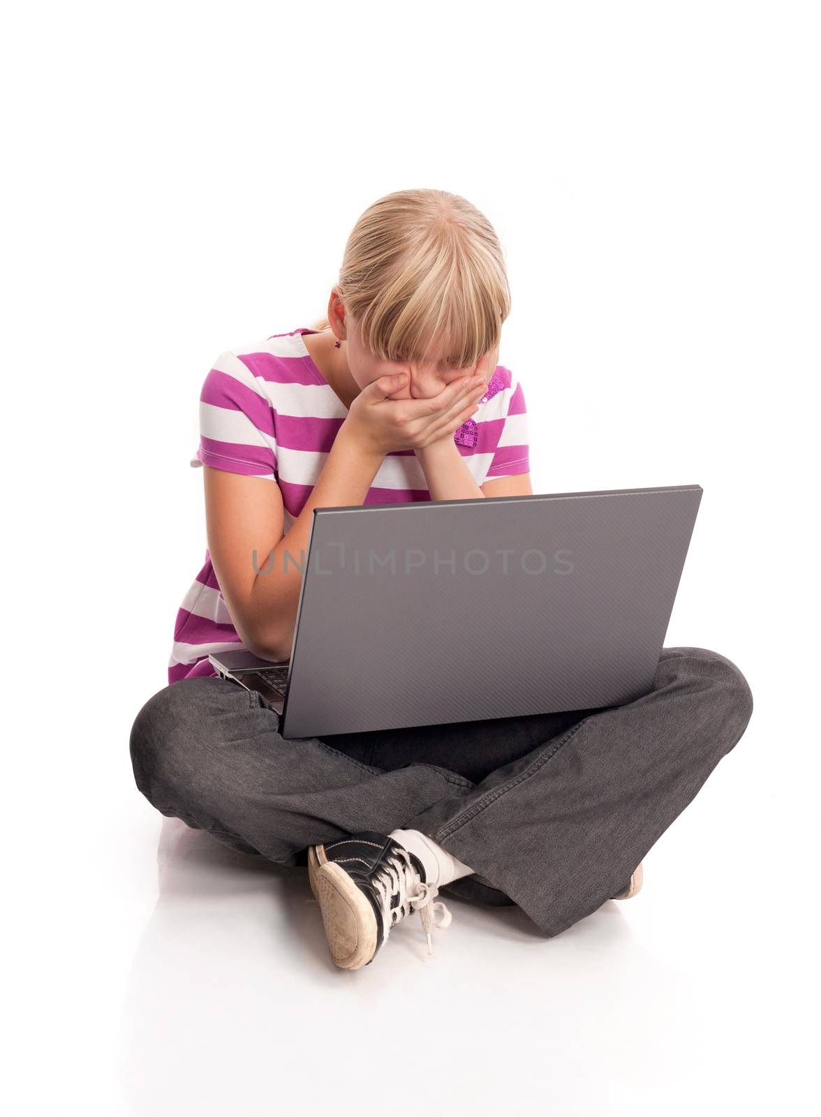 Young girl sitting on the floor and expressing negativcity emotions when using laptop