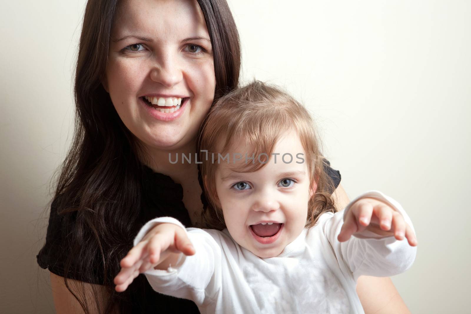 Toddler age girl sitting with her smiling mother.  