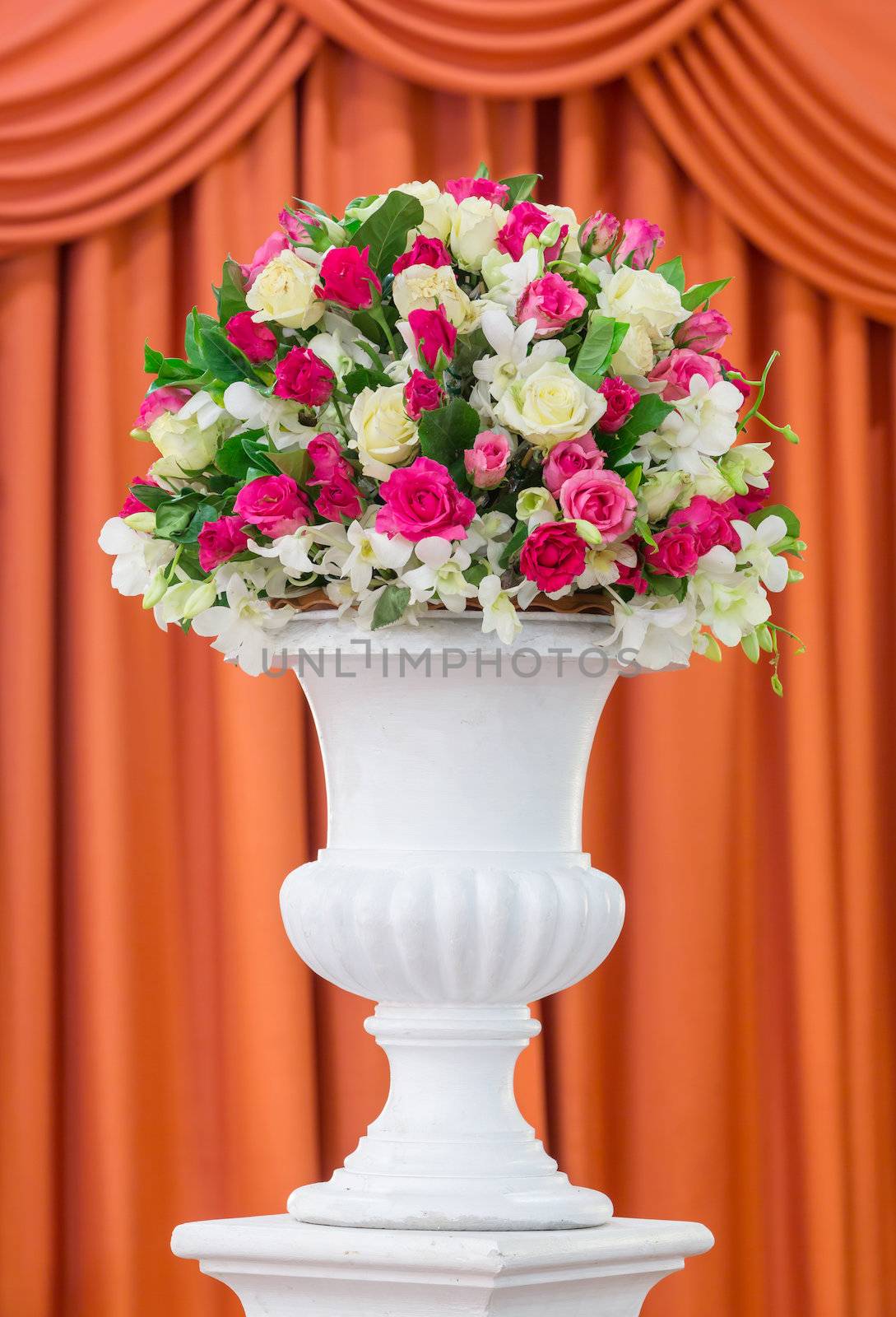 Bouquet of flowers in old fashion vase isolated on red curtain