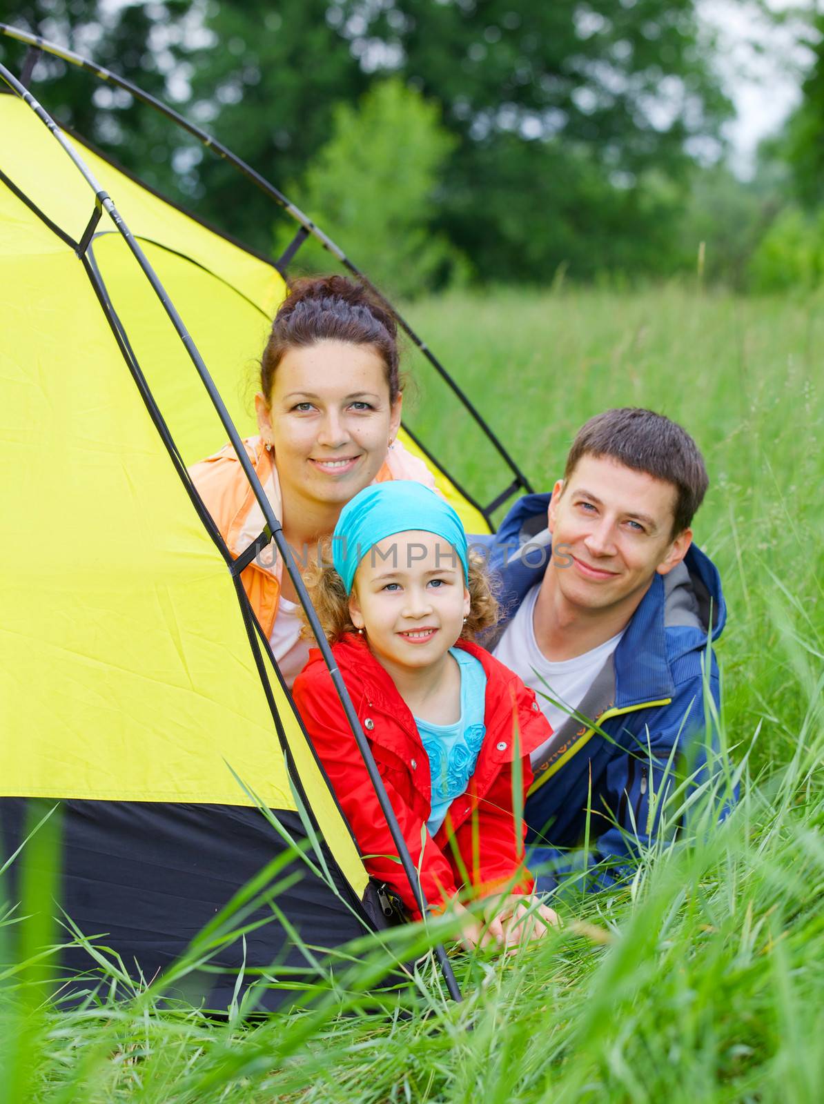 Summer vacation. Family of three in tent in camping on the nature. Vertical view