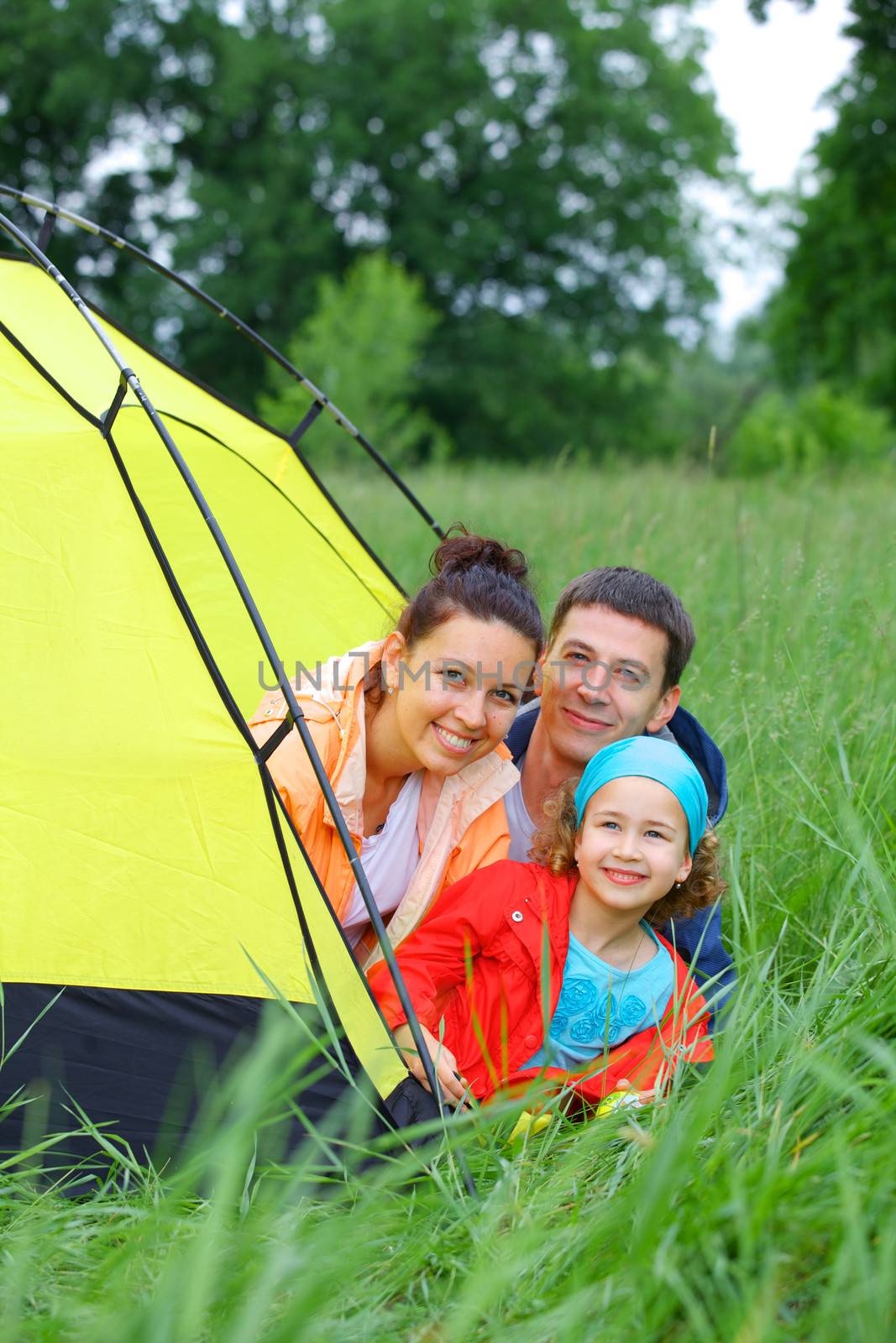 Summer vacation. Family of three in tent in camping on the nature. Vertical view