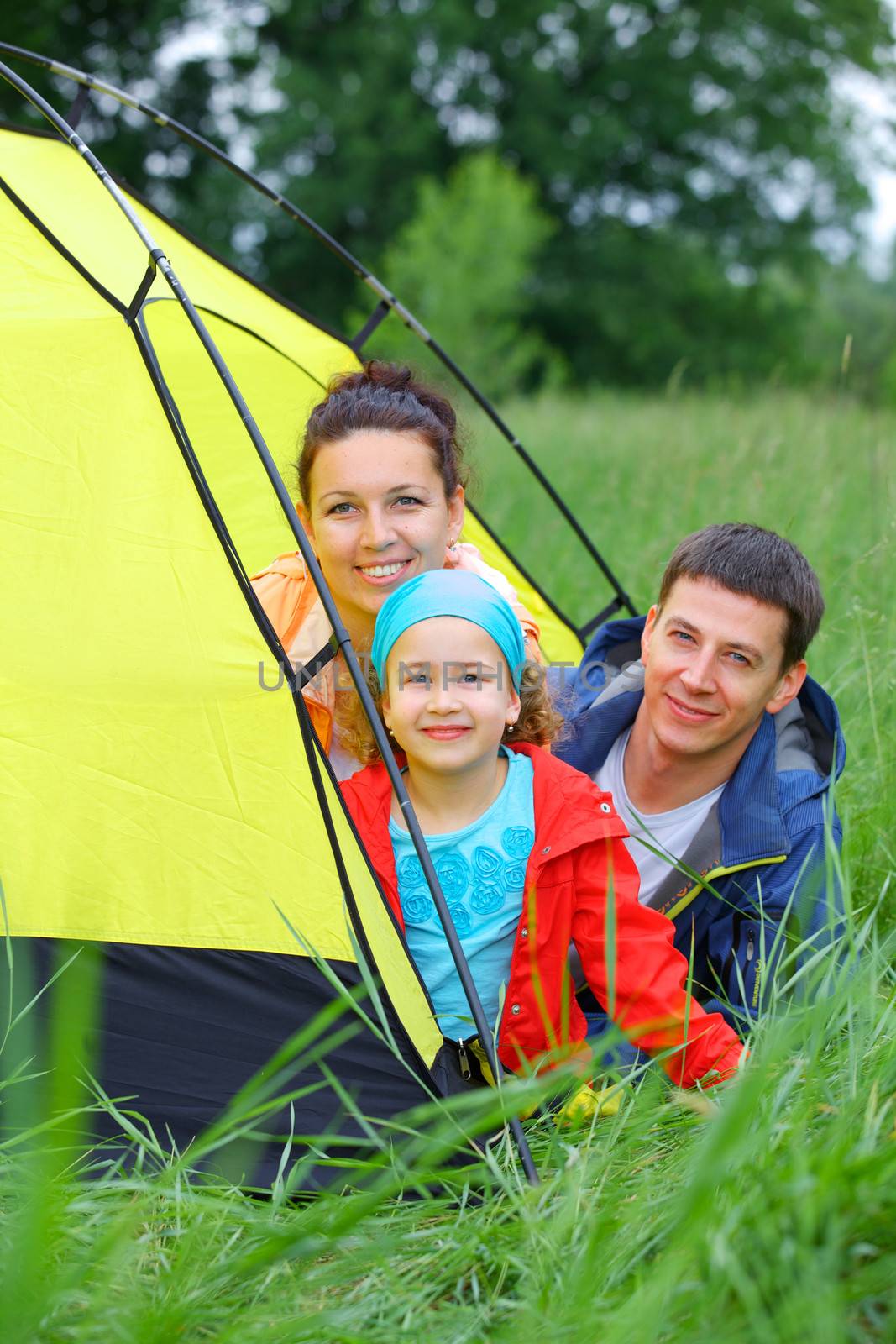 Summer vacation. Family of three in tent in camping on the nature. Vertical view