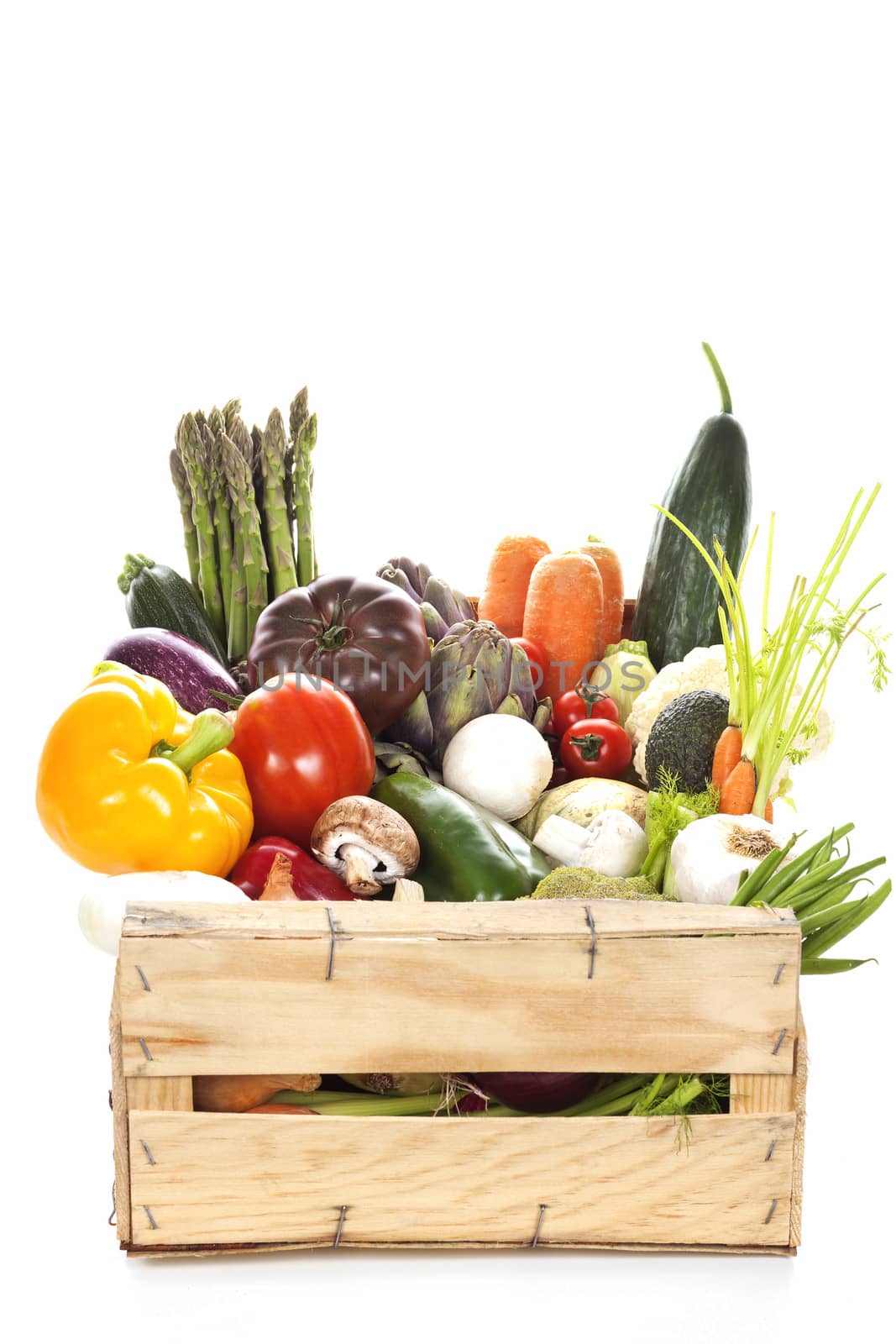 Assortment of fresh vegetables in a crate on white background