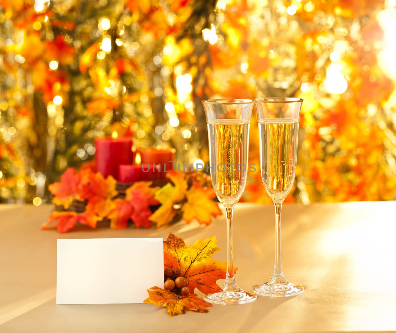 Champagne glasses for reception in front of autumn background and candles and placecard