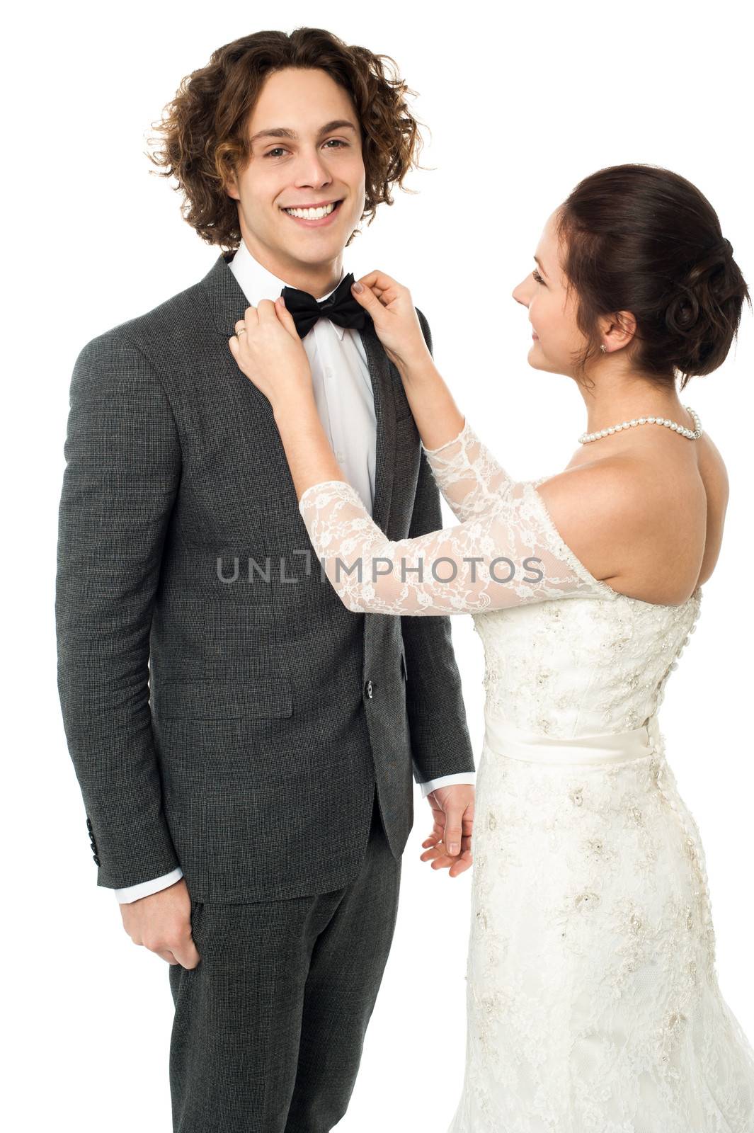 Bride adjusting her man's bow tie by stockyimages