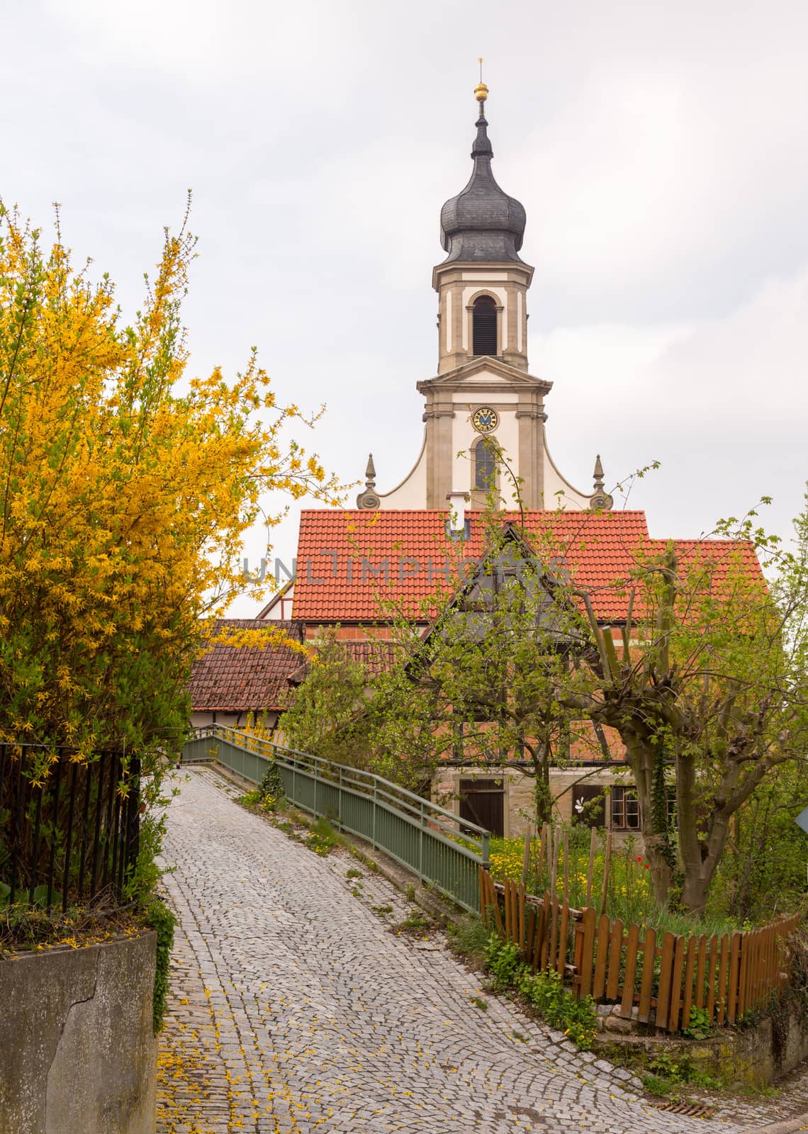 Evangelical Lutheran church of St Johannis or Johannes in small Bavarian village of Castell in Germany. Church rises above trees from surrounding vineyards of Castell winery.