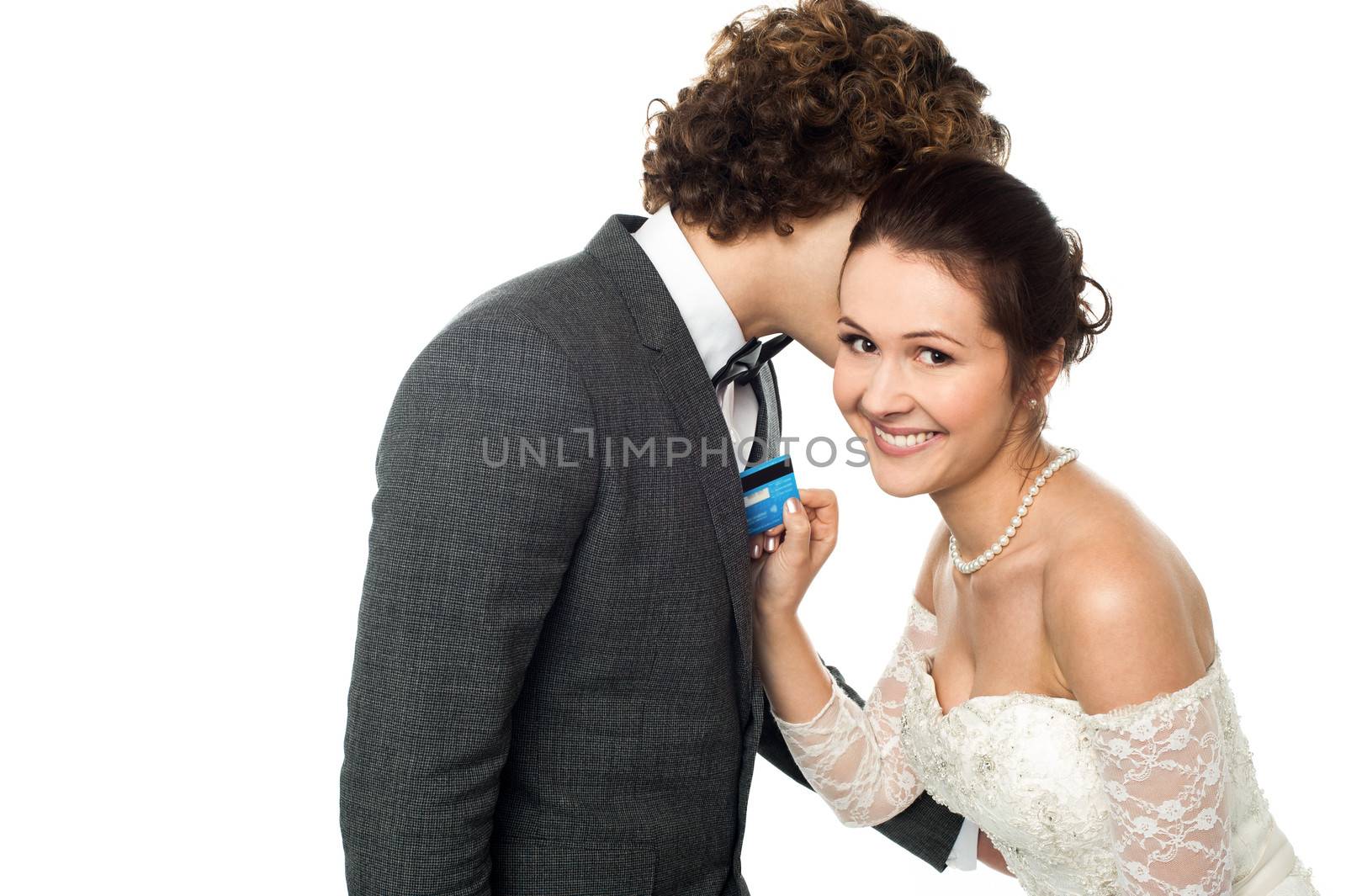 Young groom whispering into the ears of a gorgeous bride holding cash card