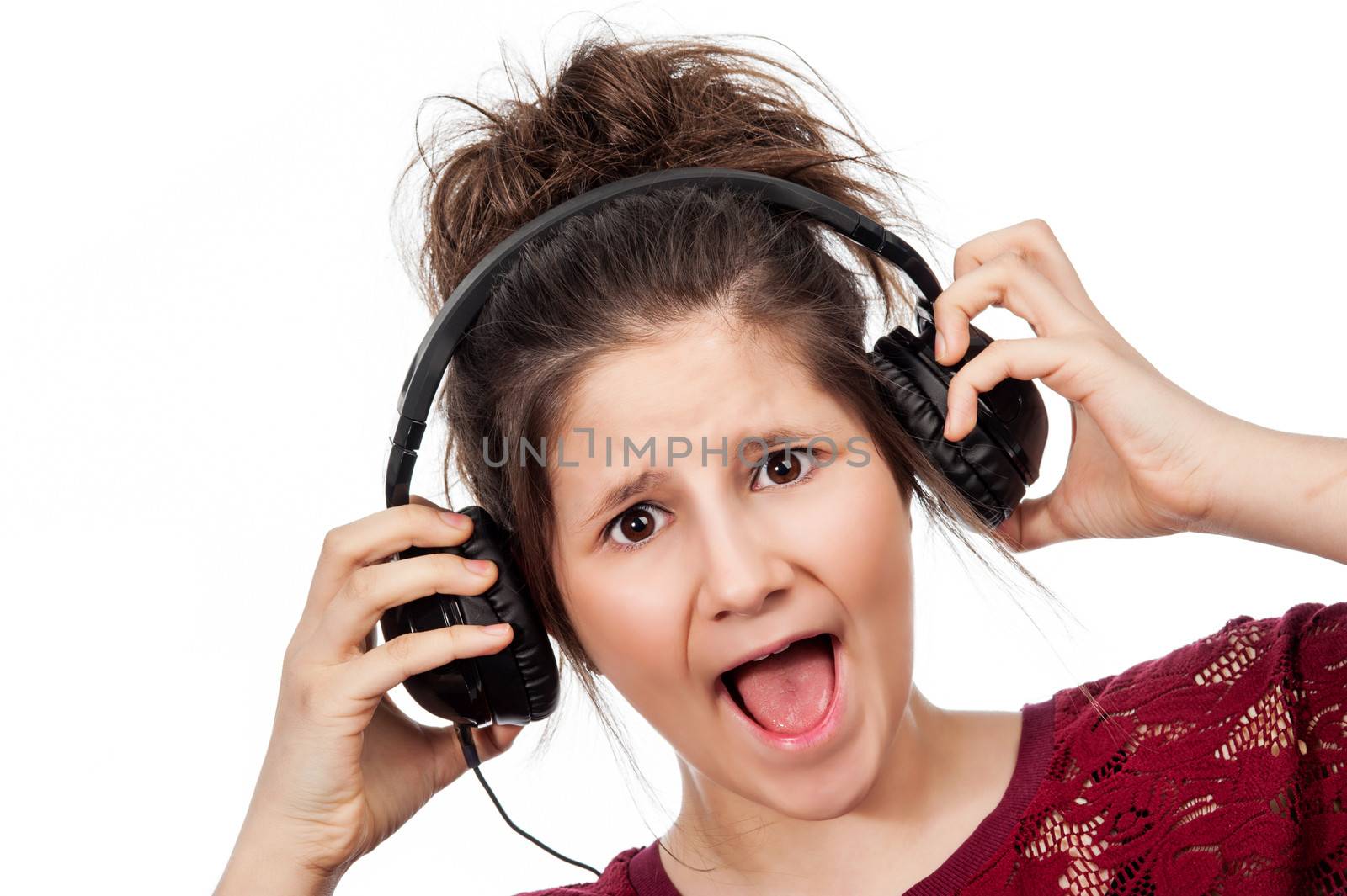 Teenage girl shocked at lound music with headphones in studio on white background.