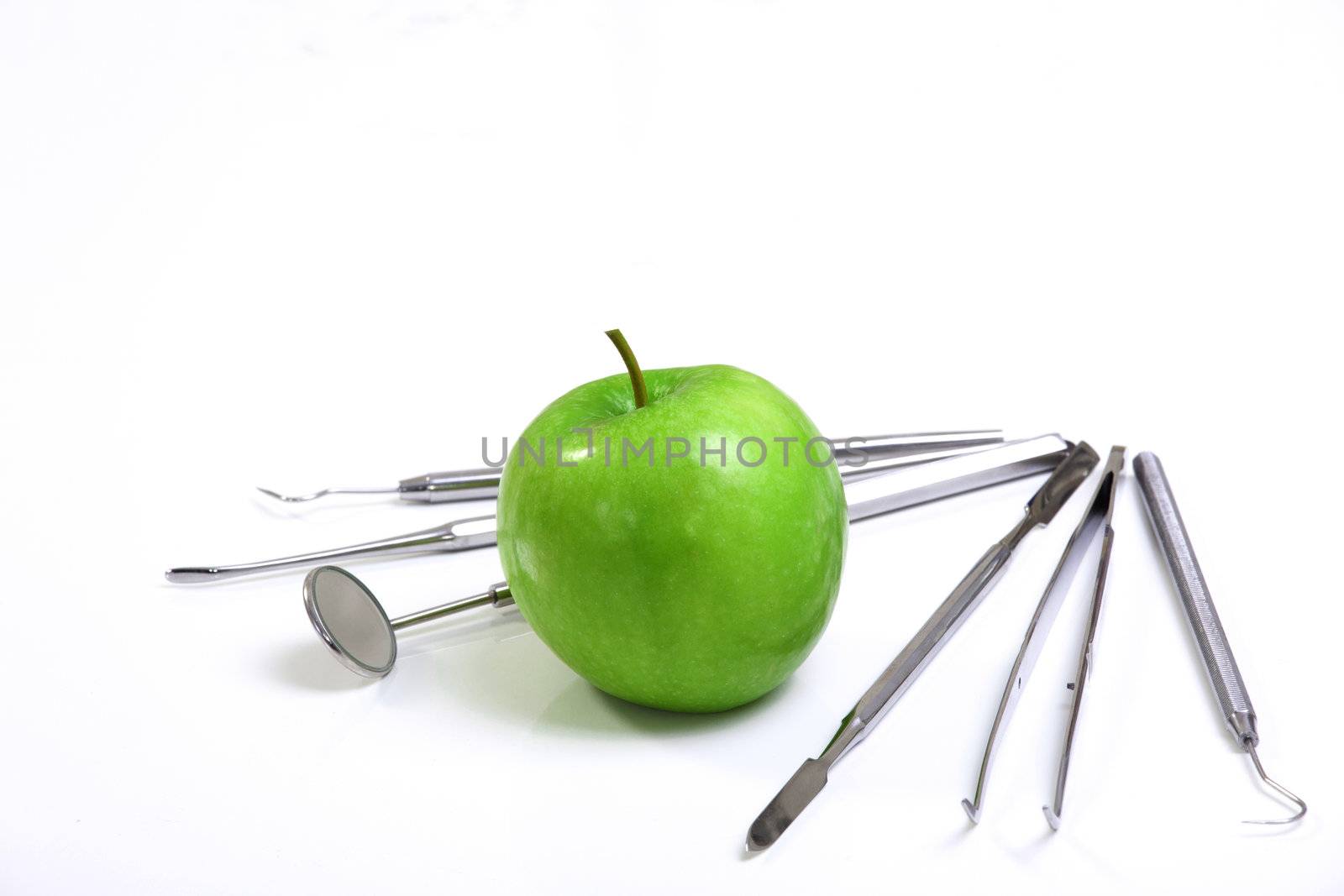 Green apple and dental tools isolated on white