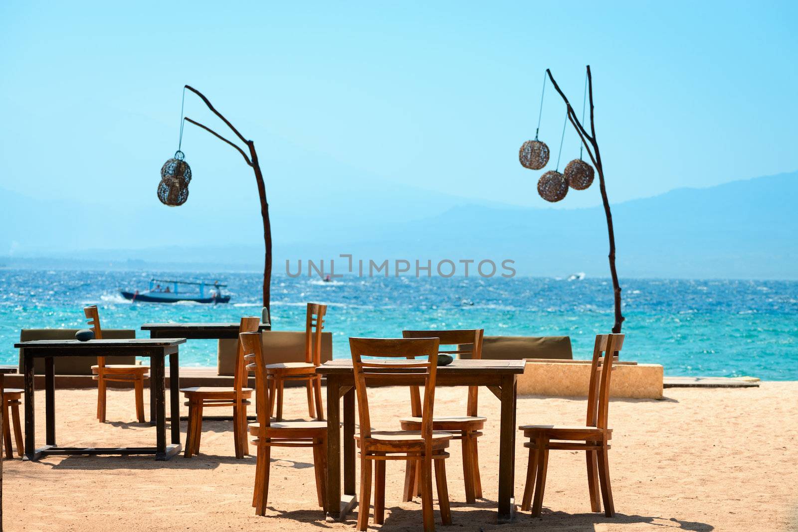 Outdoor cafe on the beach with blue ocean and sky on background