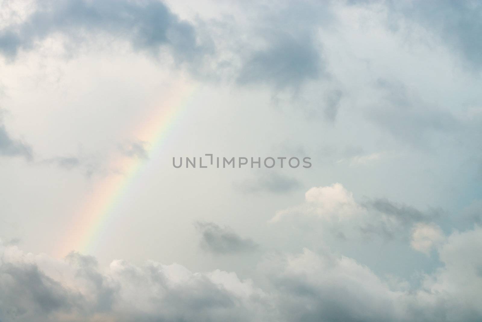 Dark cloudy sky with rainbow after rain storm