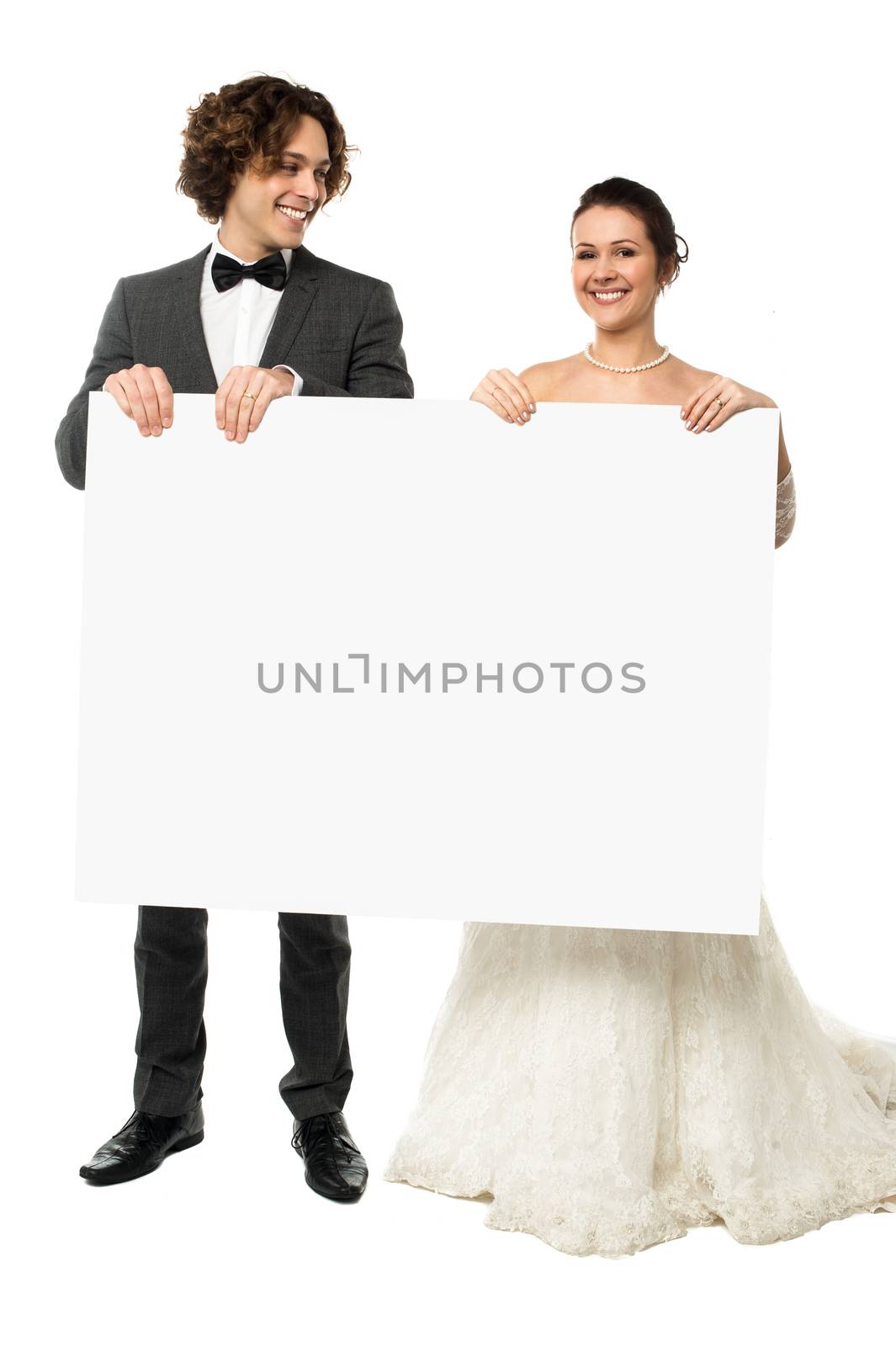Newlyweds in fine wedding trousseau displaying a blank whiteboard