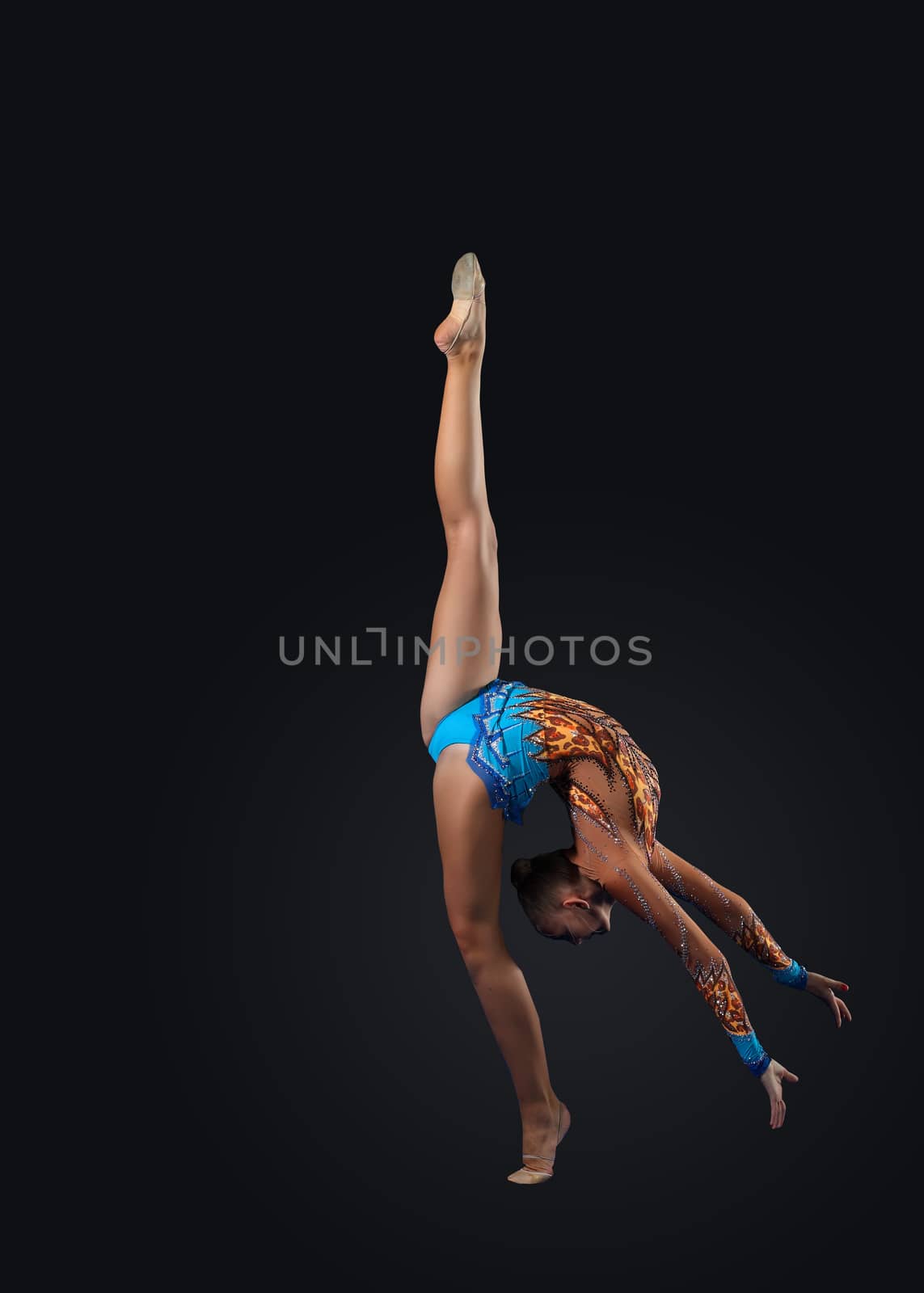 Young cute woman in gymnast suit show athletic skill on black background