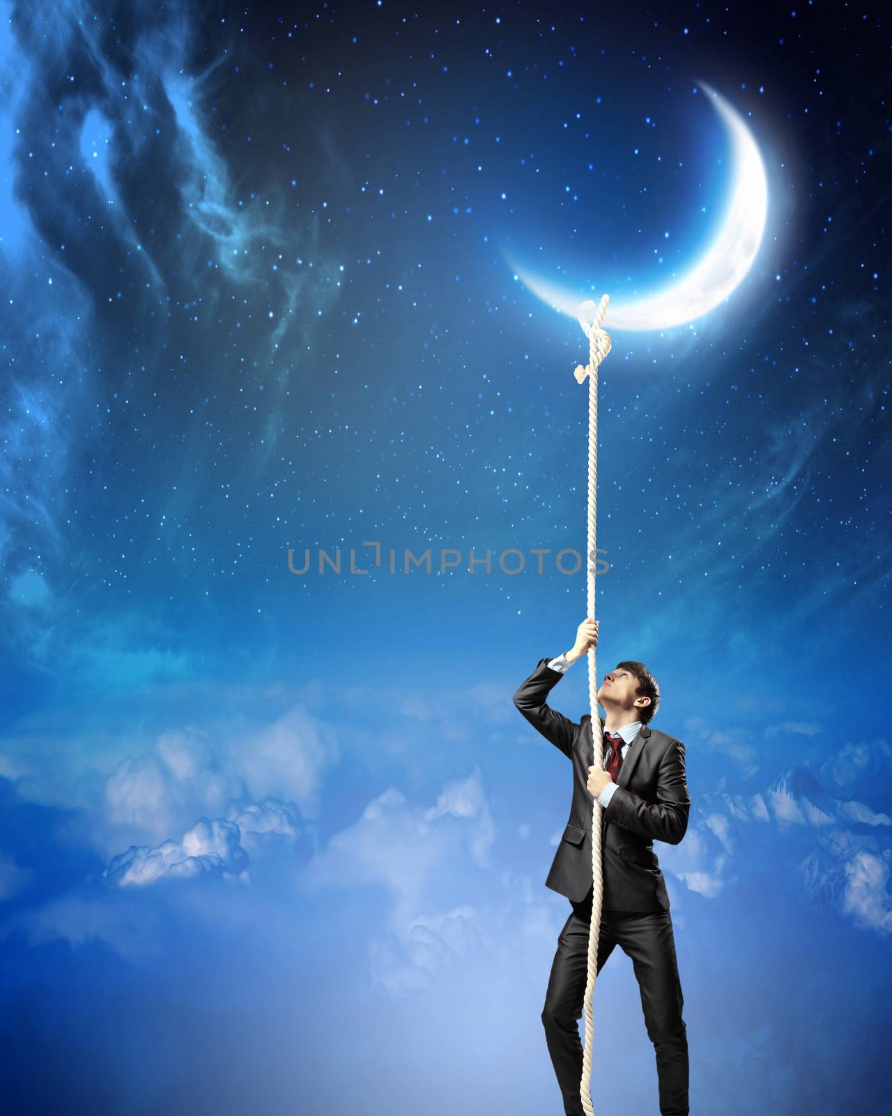 Image of businessman climbing rope attached to moon