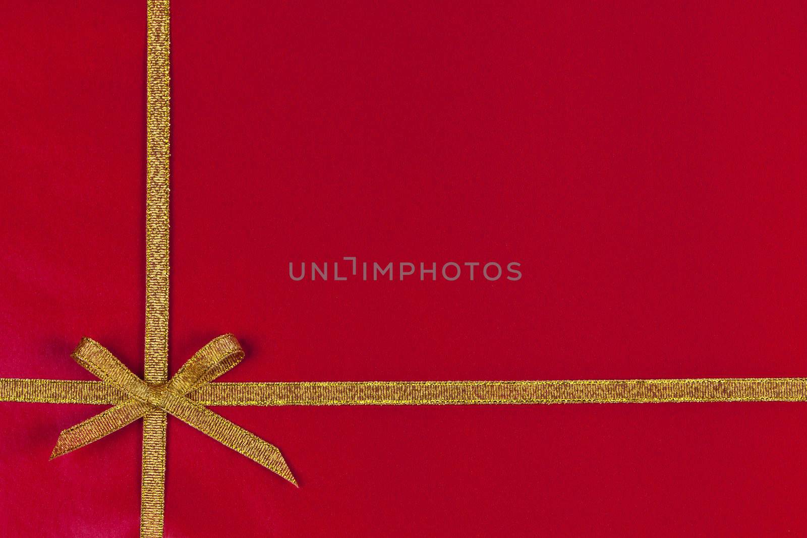 Red background of present wrapped with gold ribbon and bow