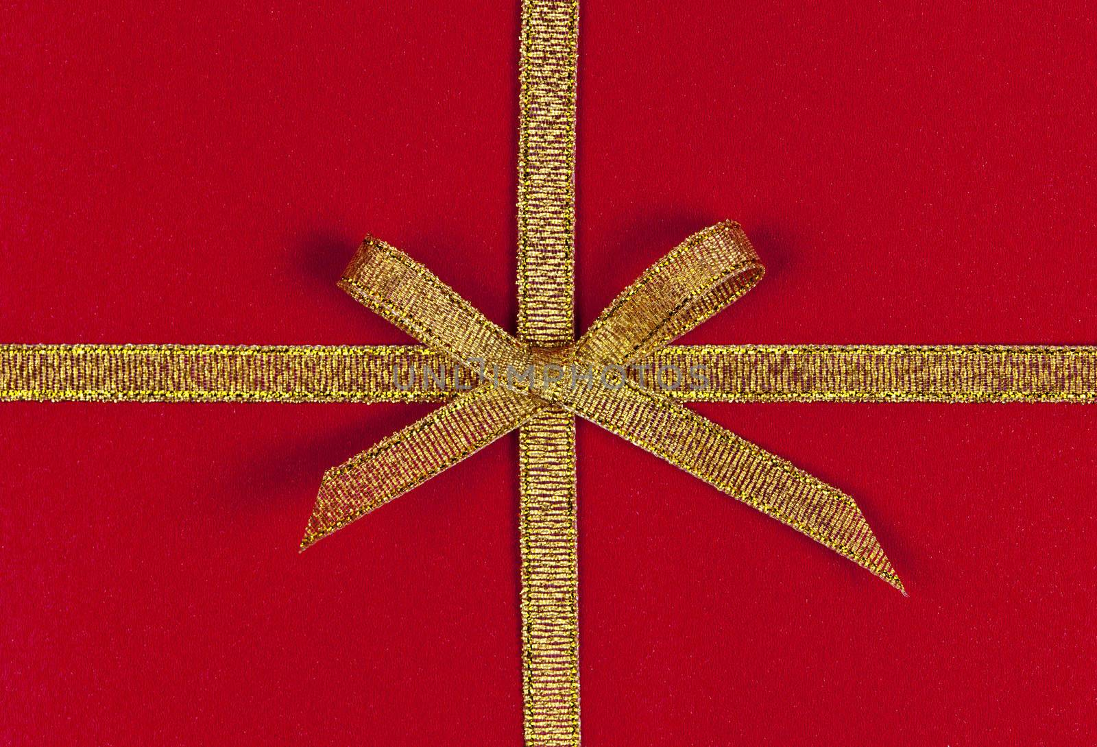 Red present wrapped with gold ribbon and bow