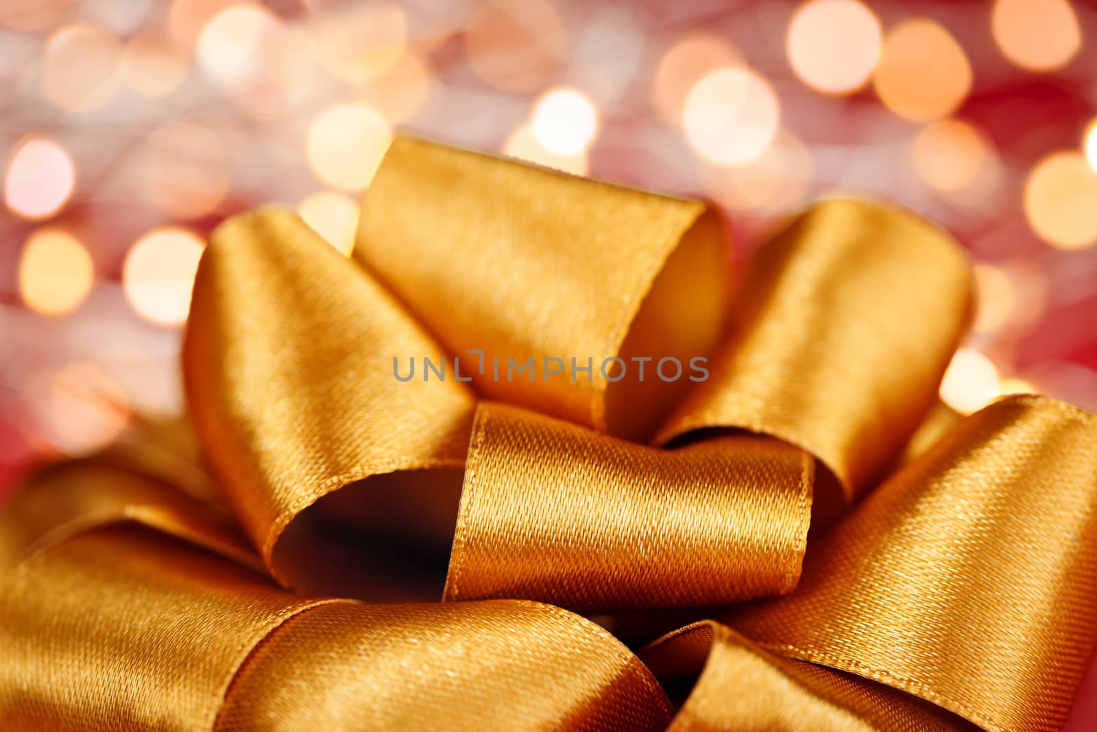 Gold gift bow with festive lights by elenathewise