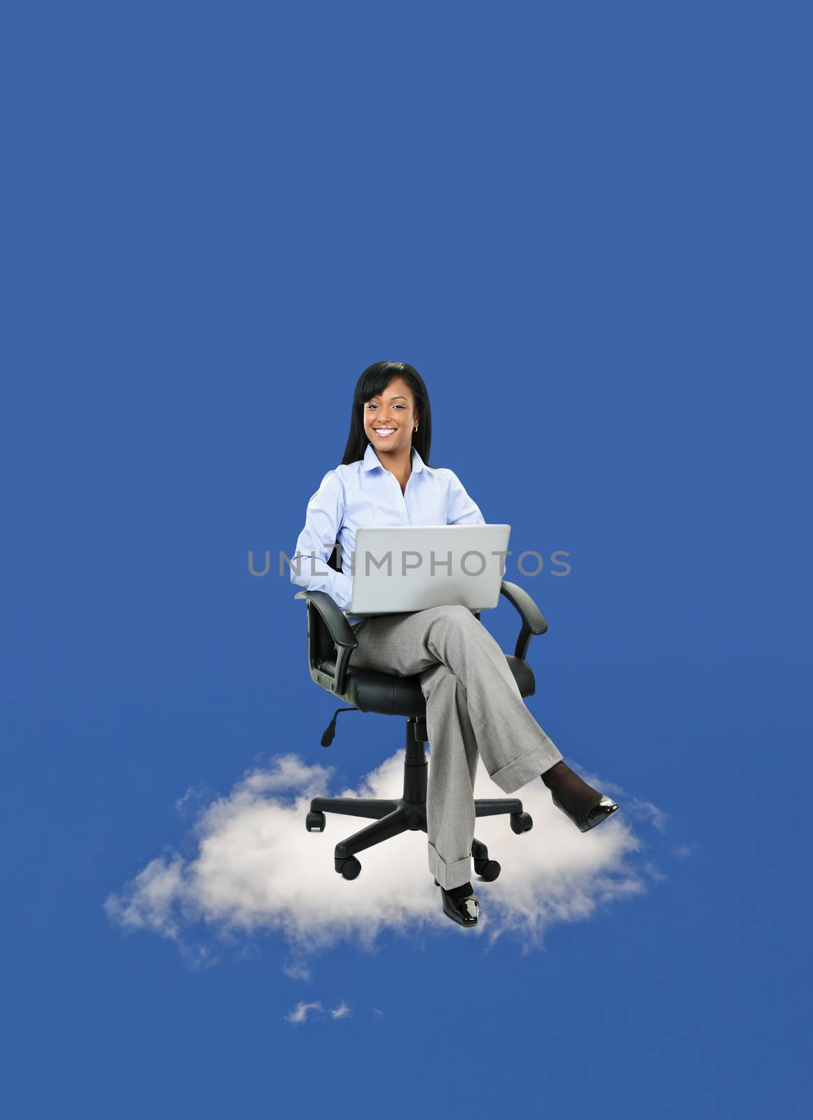 Smiling black businesswoman sitting in office chair on cloud with laptop computer